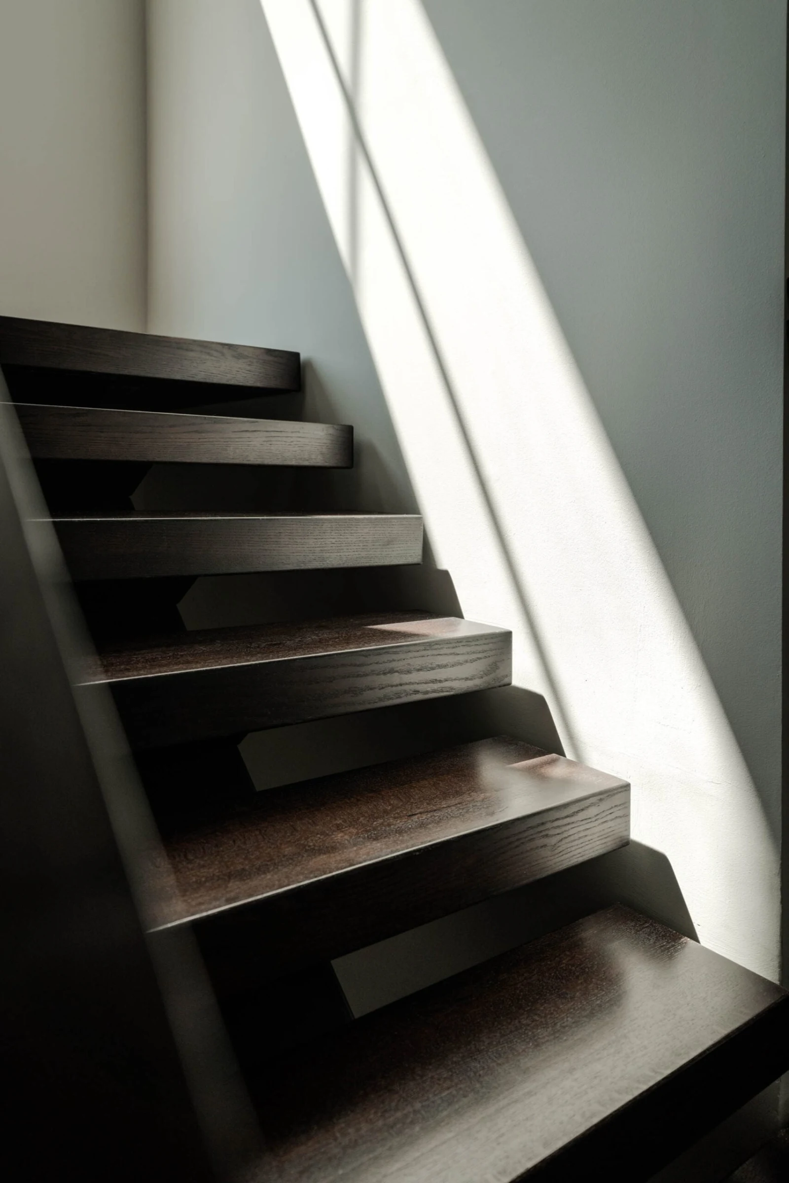 Sunlight raking across dark open risers and the thick stained treads