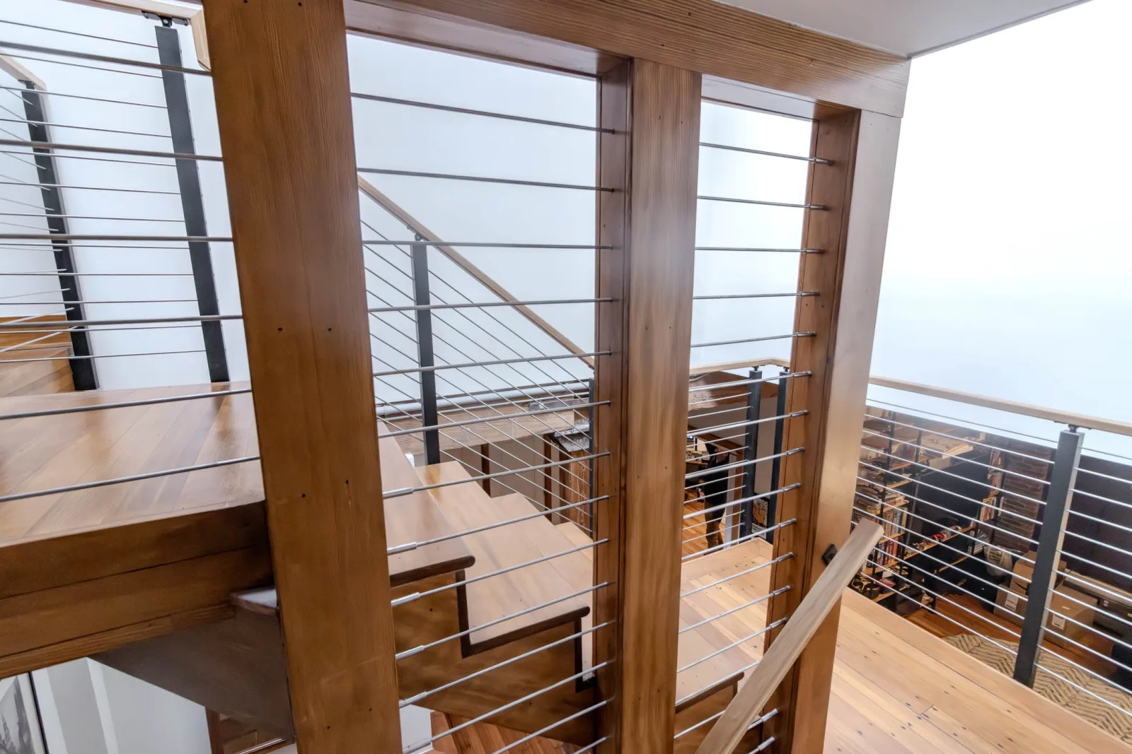 Cable railing between heavy timber posts on a loft stair and upper landing