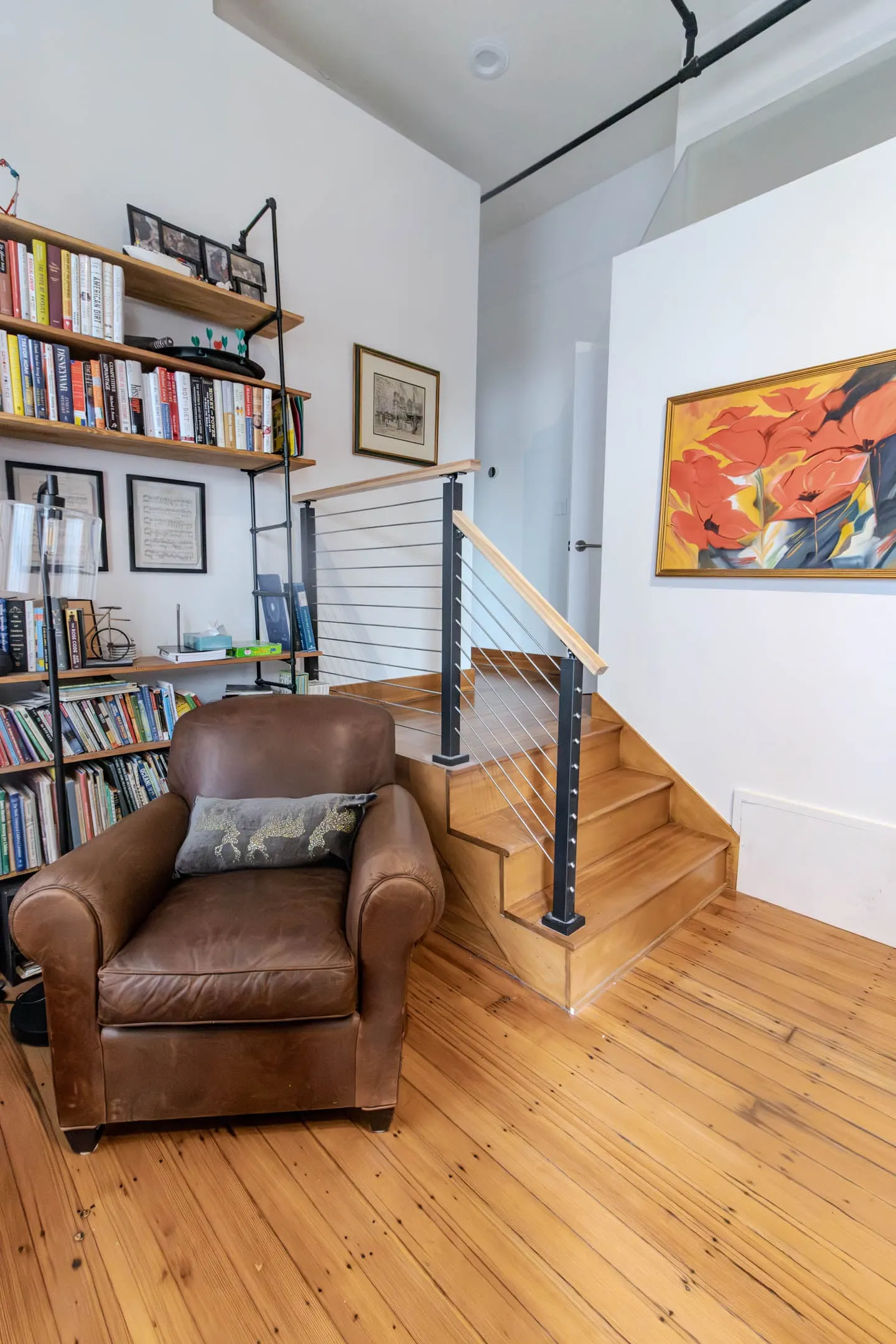 Reading nook with leather armchair beside short wood steps and a rod railing