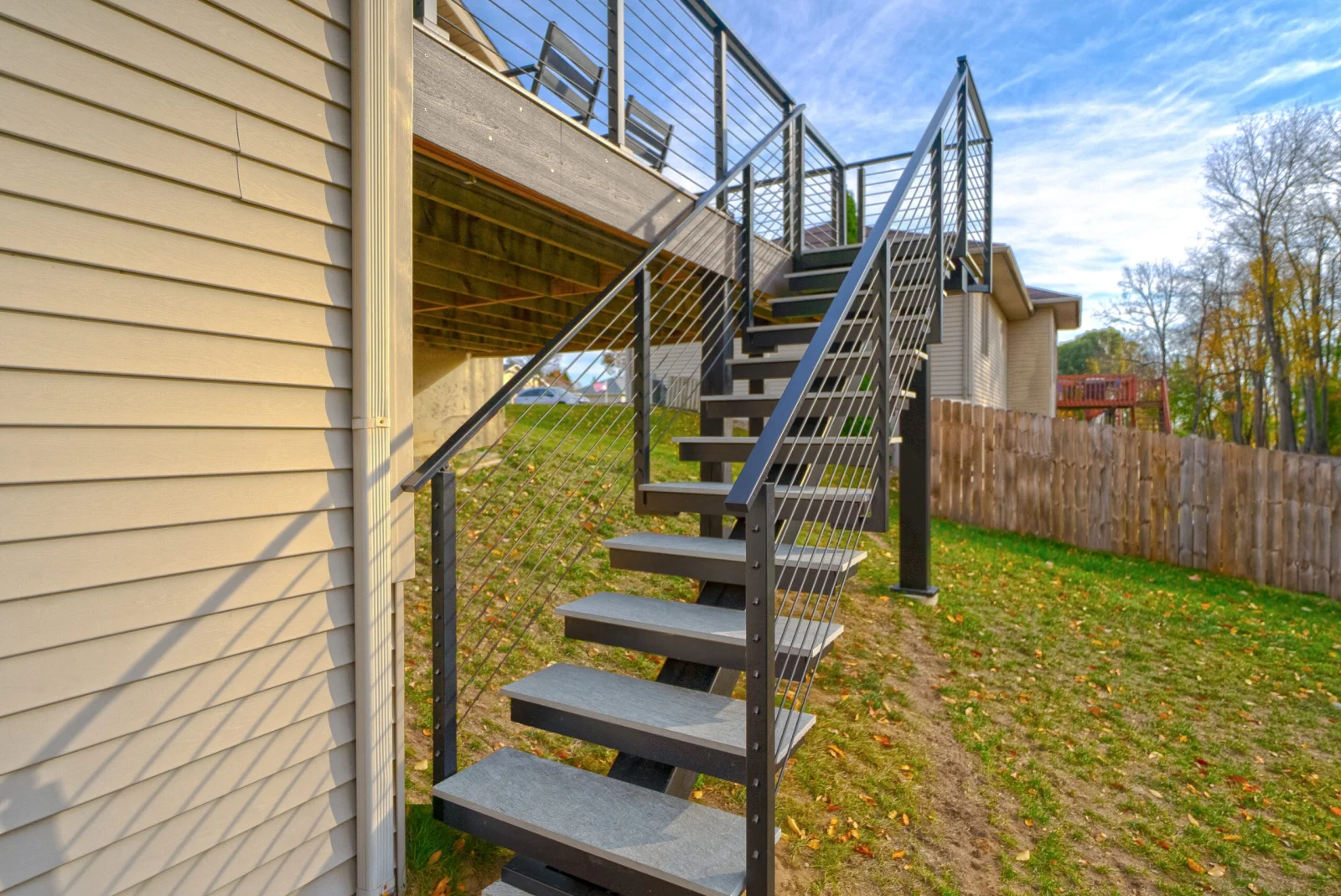 Outdoor stair climbing from the lawn to an elevated deck along the siding