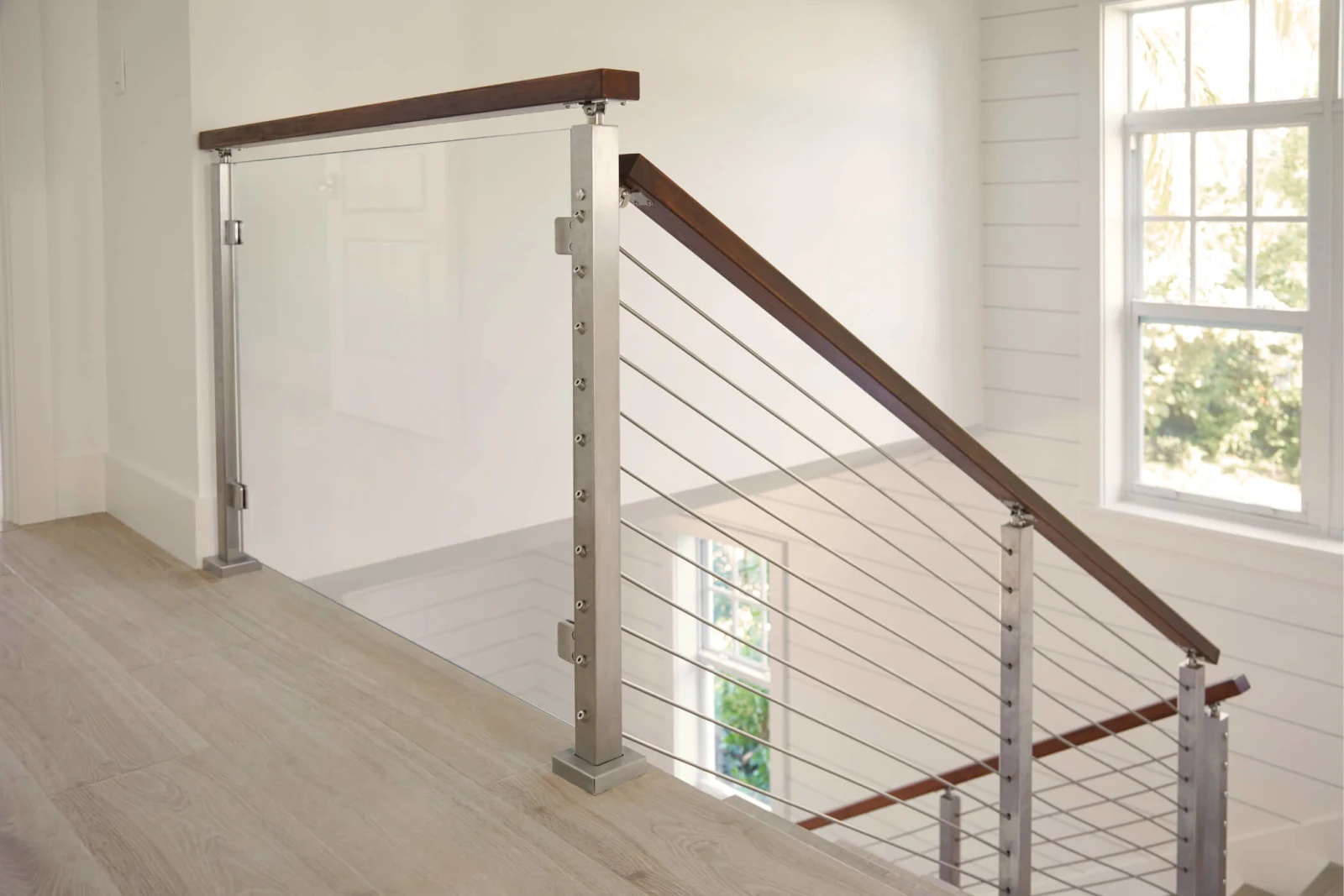 Upper hall railing with rods, glass corner panel and a sunlit window