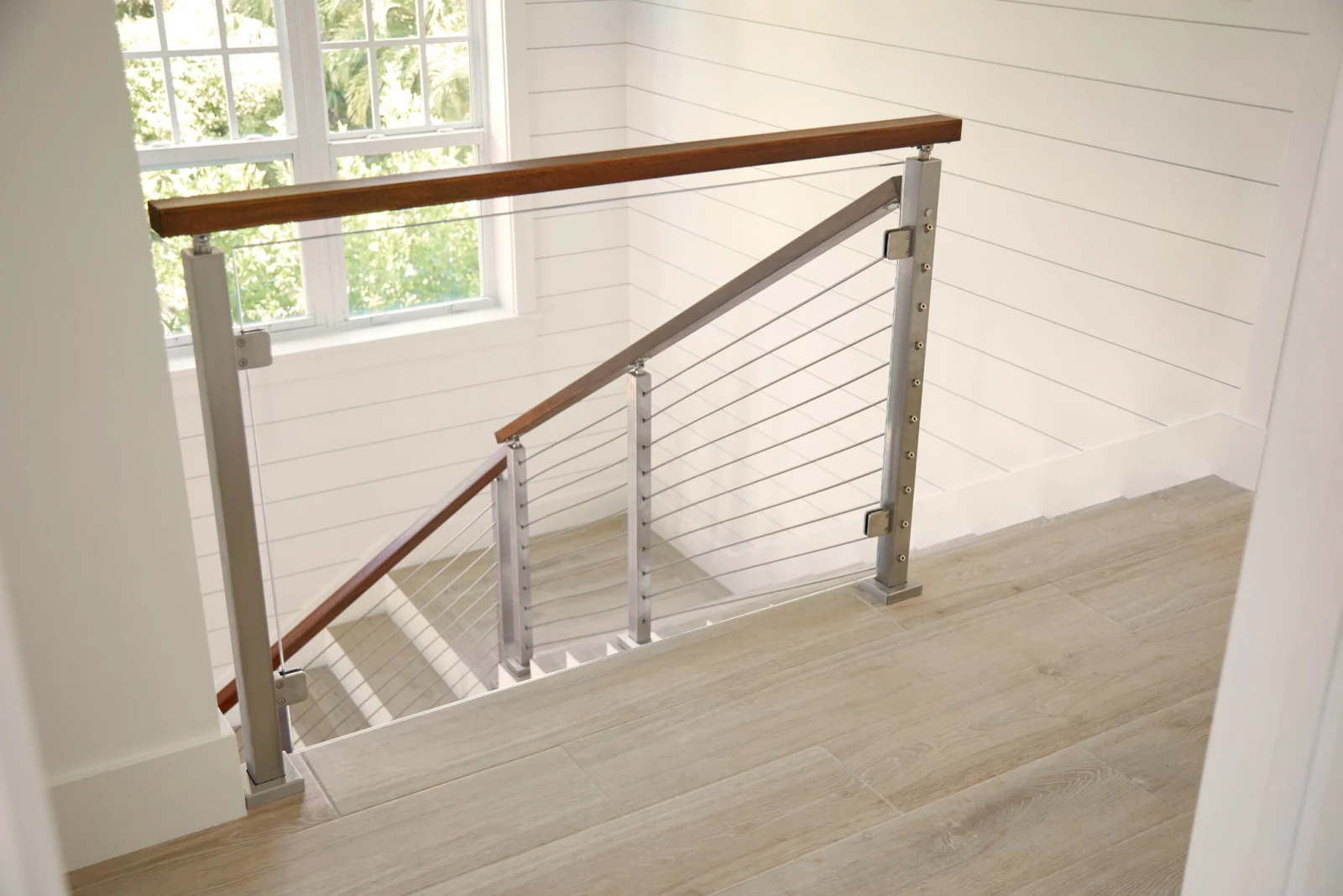 Landing railing of stainless posts and rods under a dark wood top rail