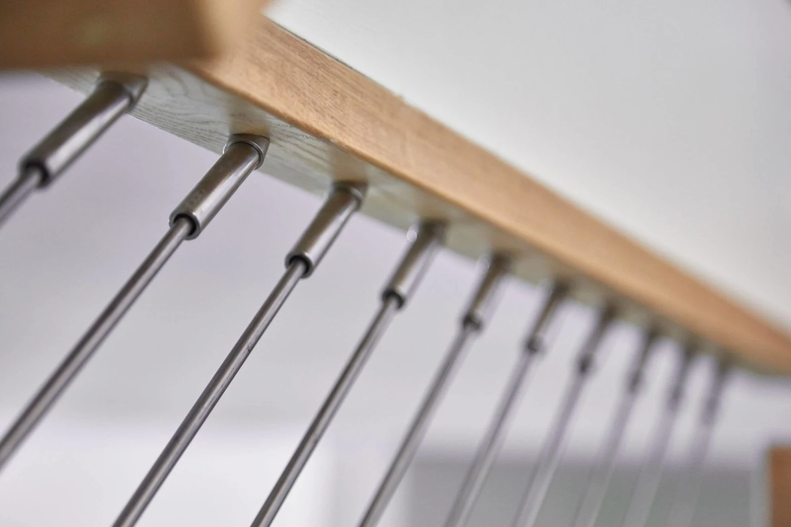 Underside of a wood top rail with vertical stainless rods and swaged fittings