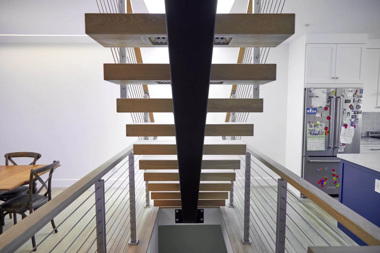 Straight-on view up a black center stringer carrying open wood treads