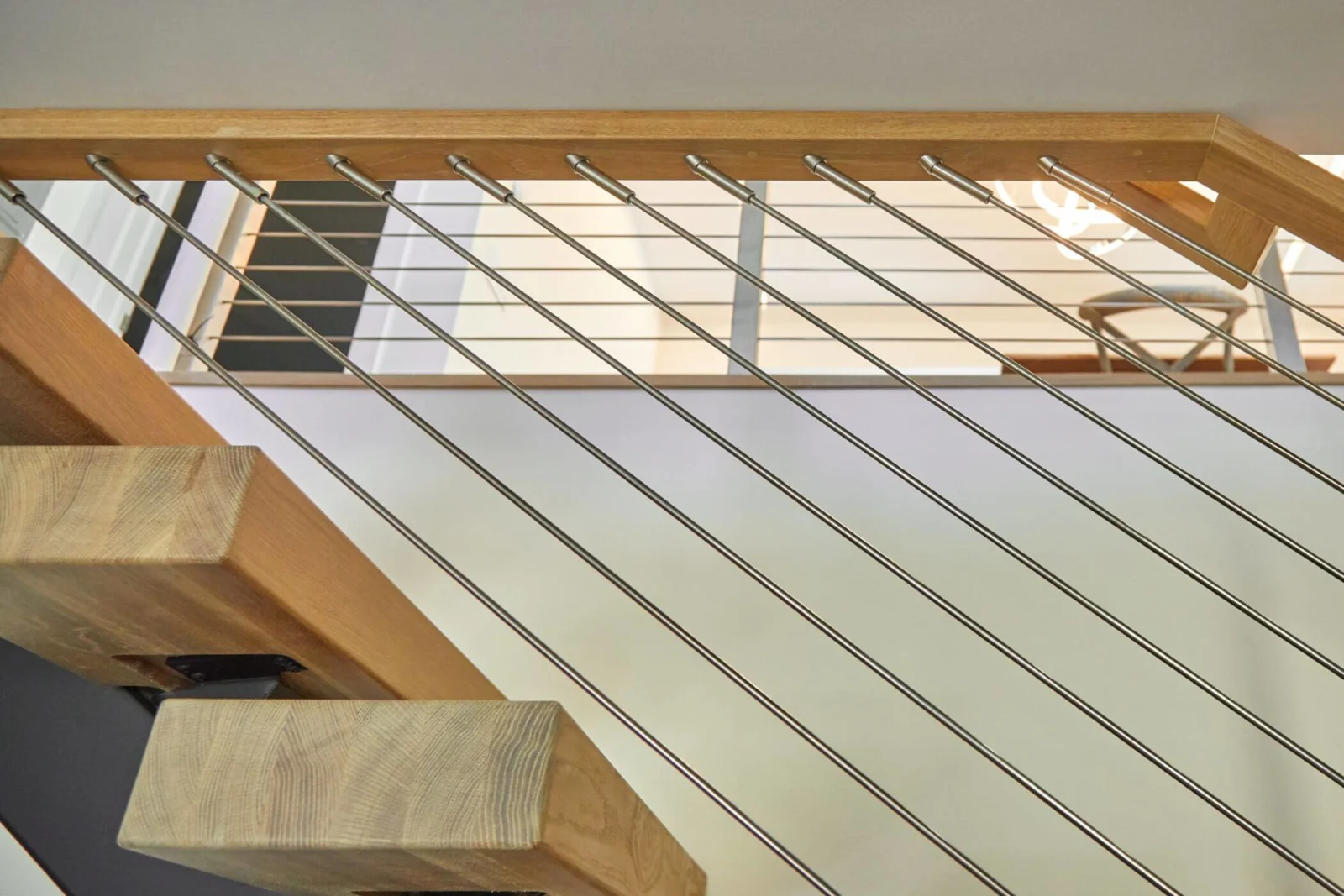Looking up through angled rods at thick wood treads and a wood top rail