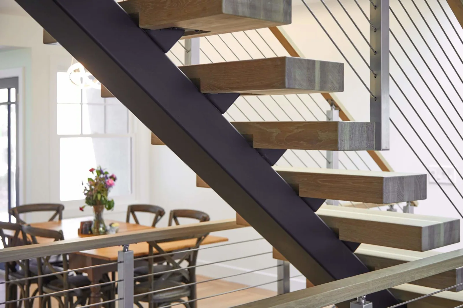 Dark center stringer seen from the side supporting thick treads above a dining room