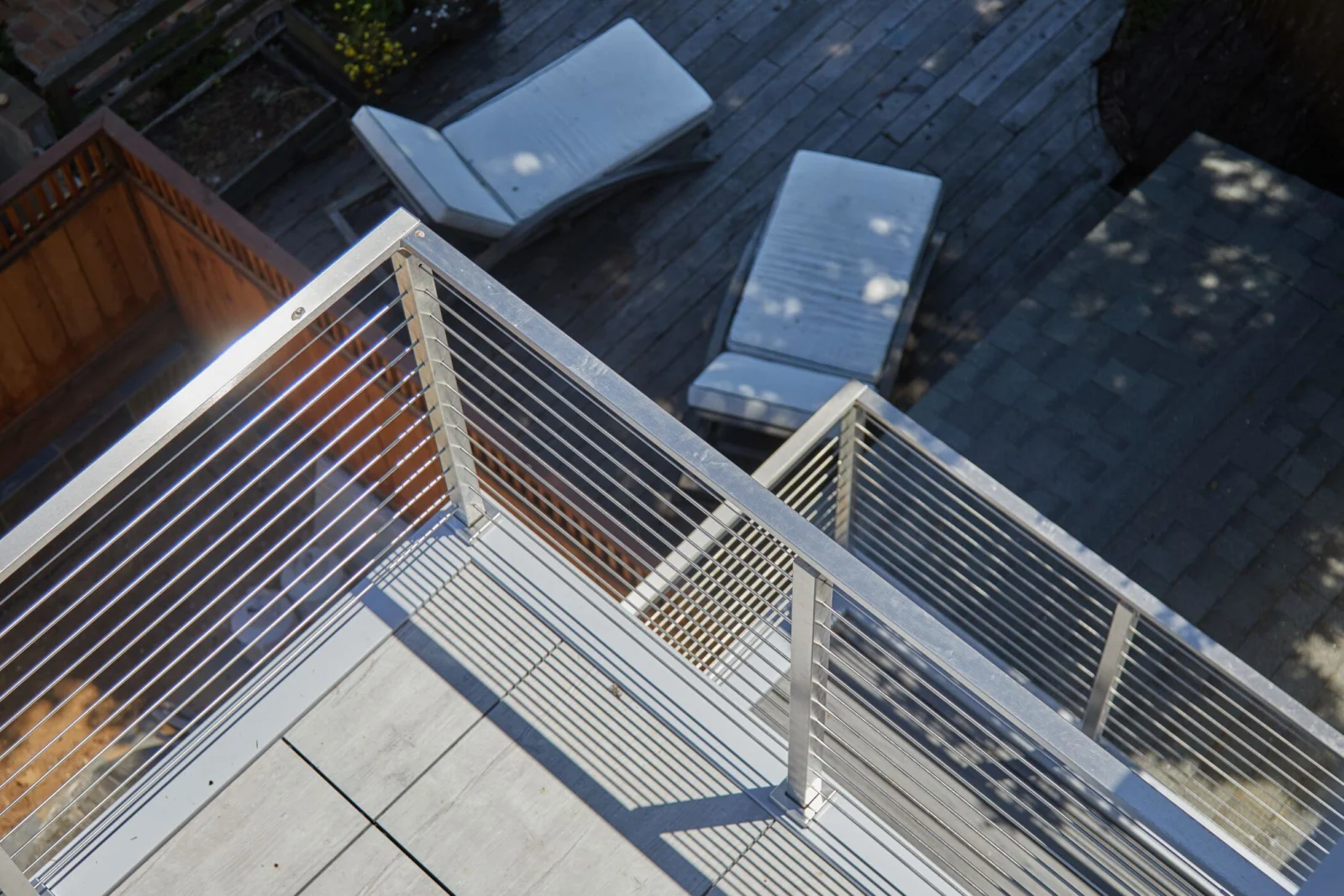 Looking down at a rooftop deck corner with vertical rod infill and lounge chairs