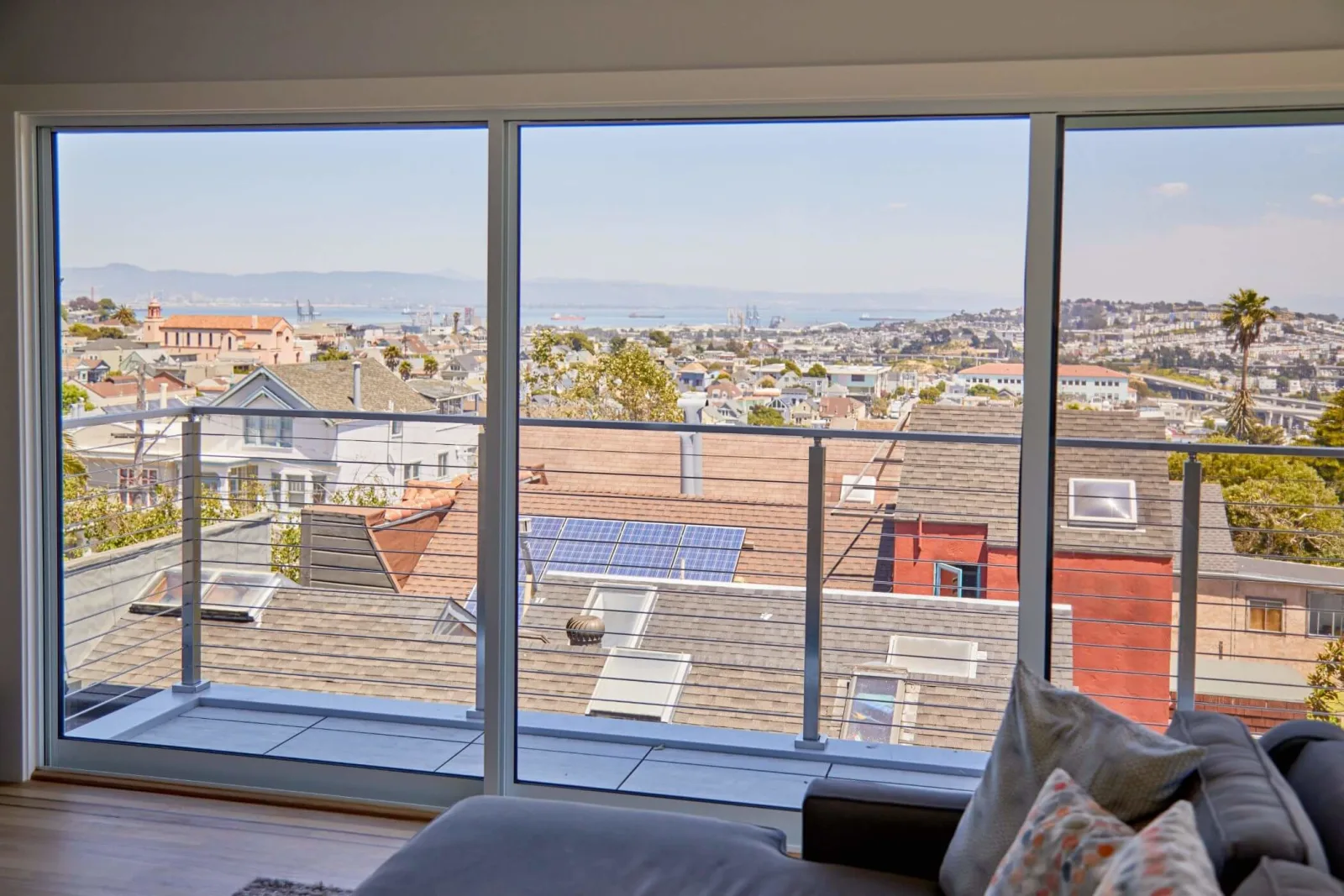 Sliding glass doors framing a balcony rod railing above a hillside neighborhood