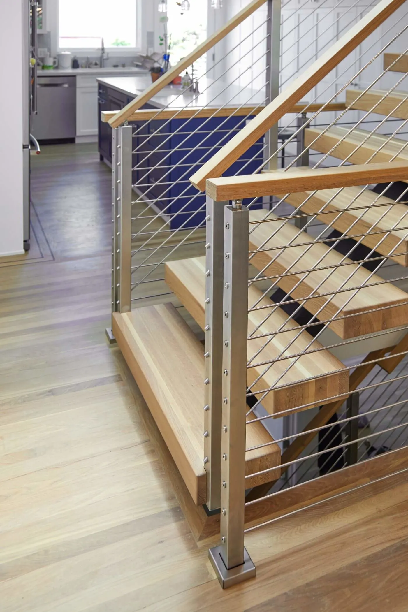 Base of a floating stair with brushed posts, rods and a wood handrail