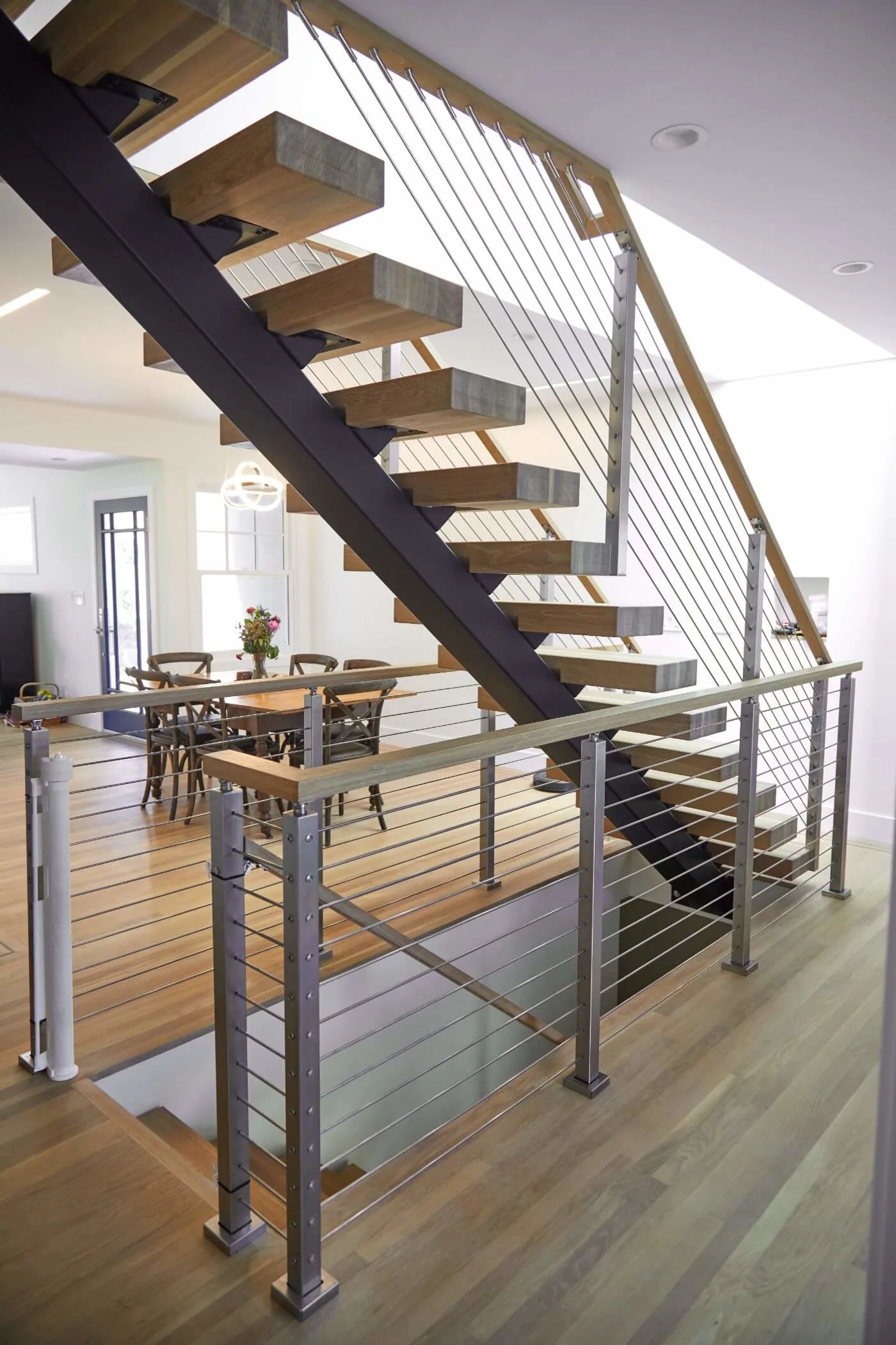 Floating stair and landing railing viewed from a wide-plank wood floor