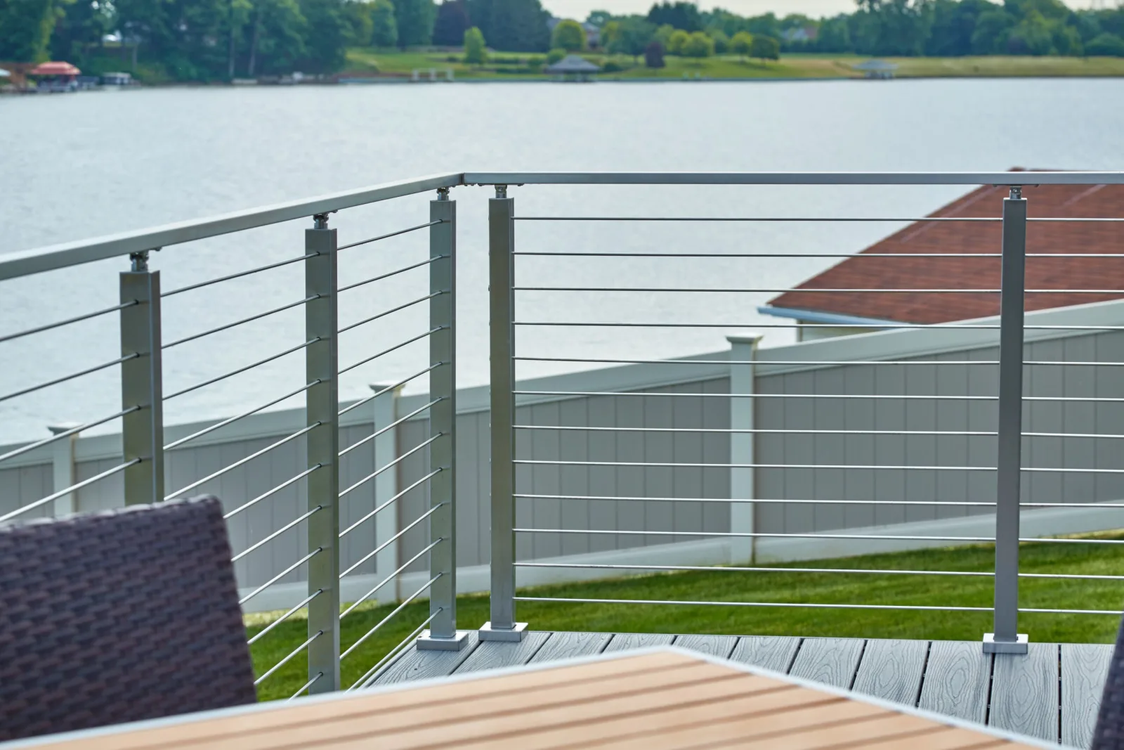 Deck seating behind a rod railing that opens onto the lake beyond