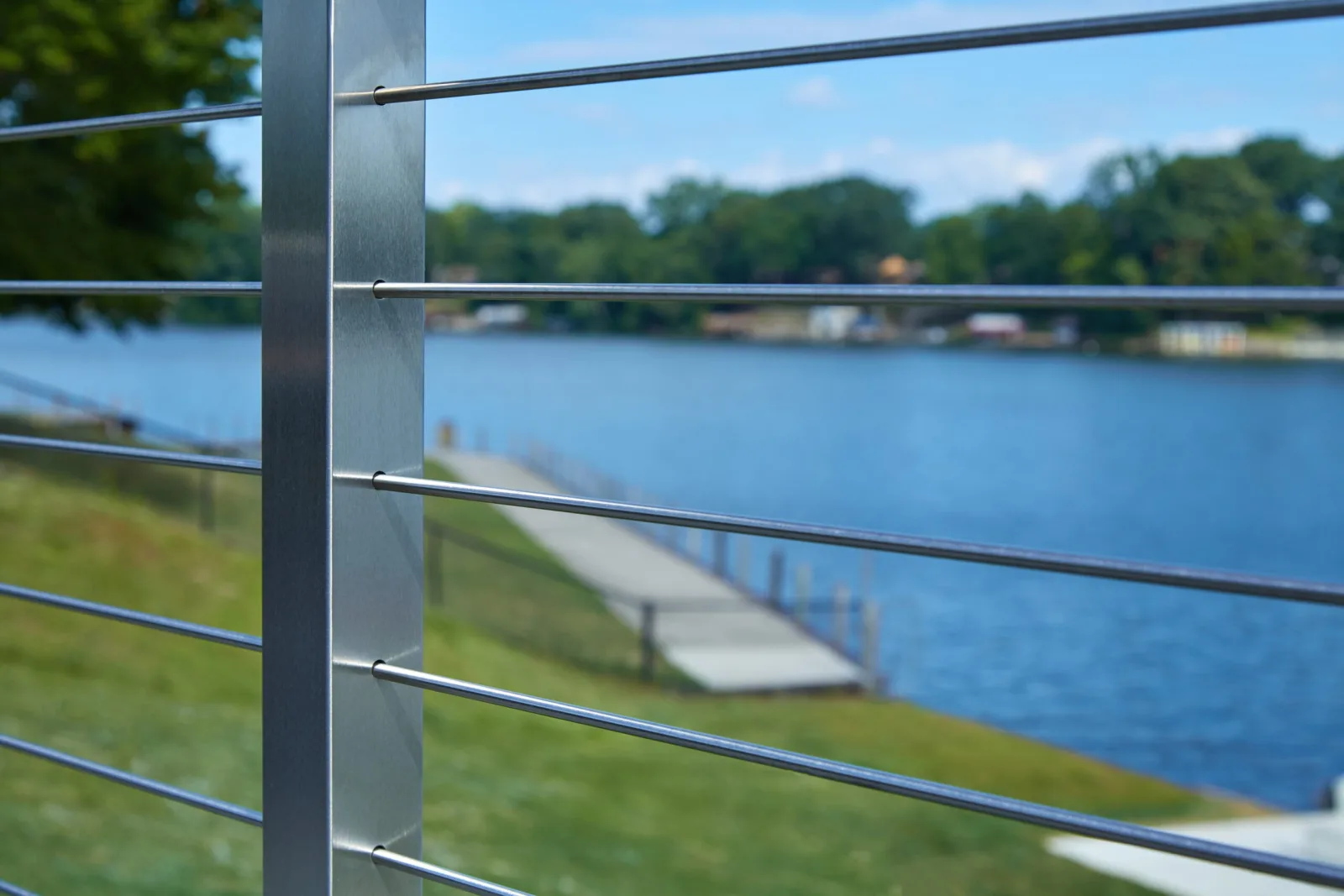 Post and horizontal rods in sharp focus with a lake and pier behind