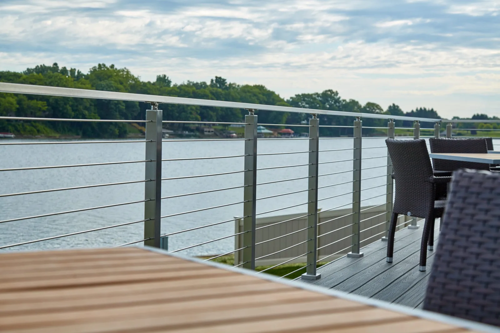 Dining tables set along a rod railing overlooking a calm lake