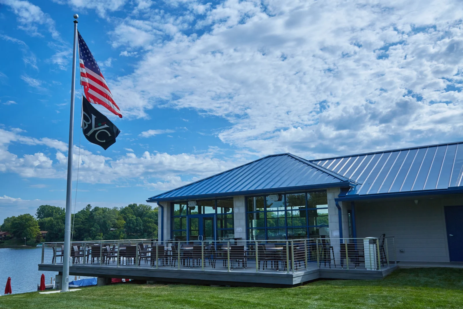 Lakeside clubhouse with a railed dining deck and a flagpole flying two flags