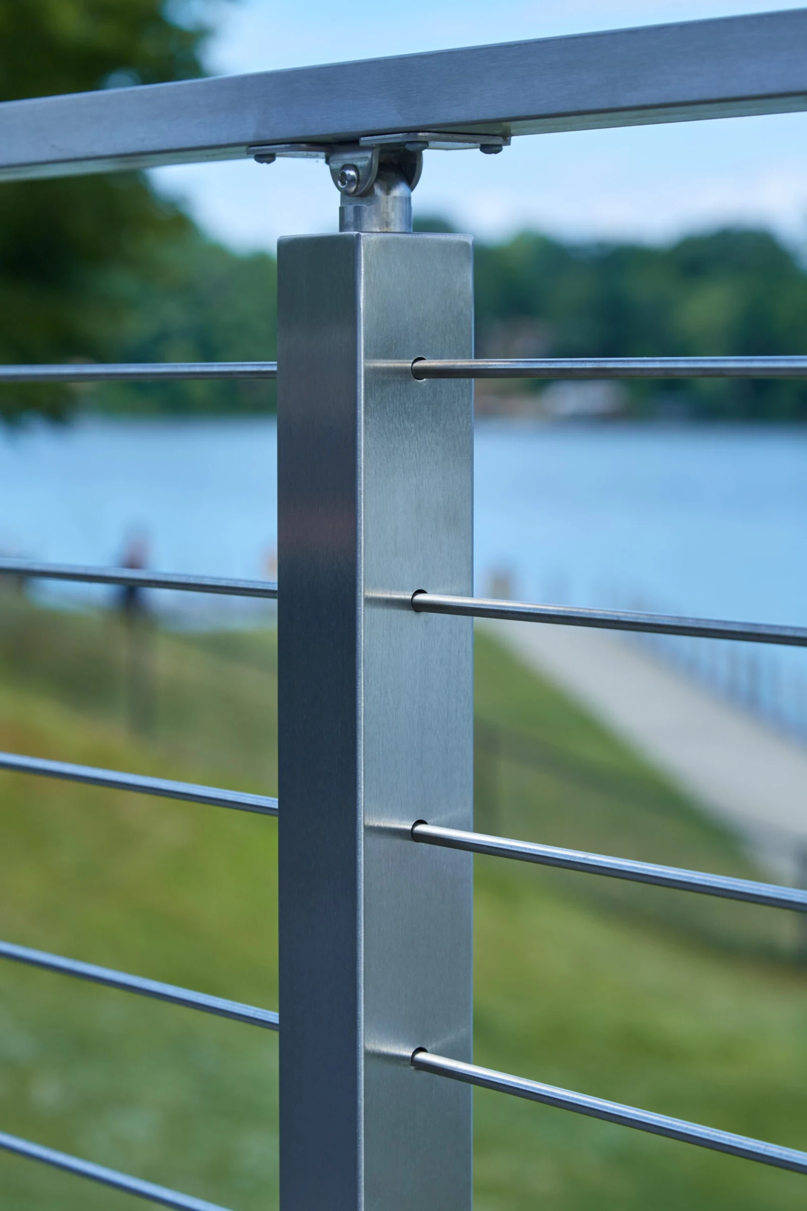 Brushed post threaded with rods above a lawn sloping toward the water