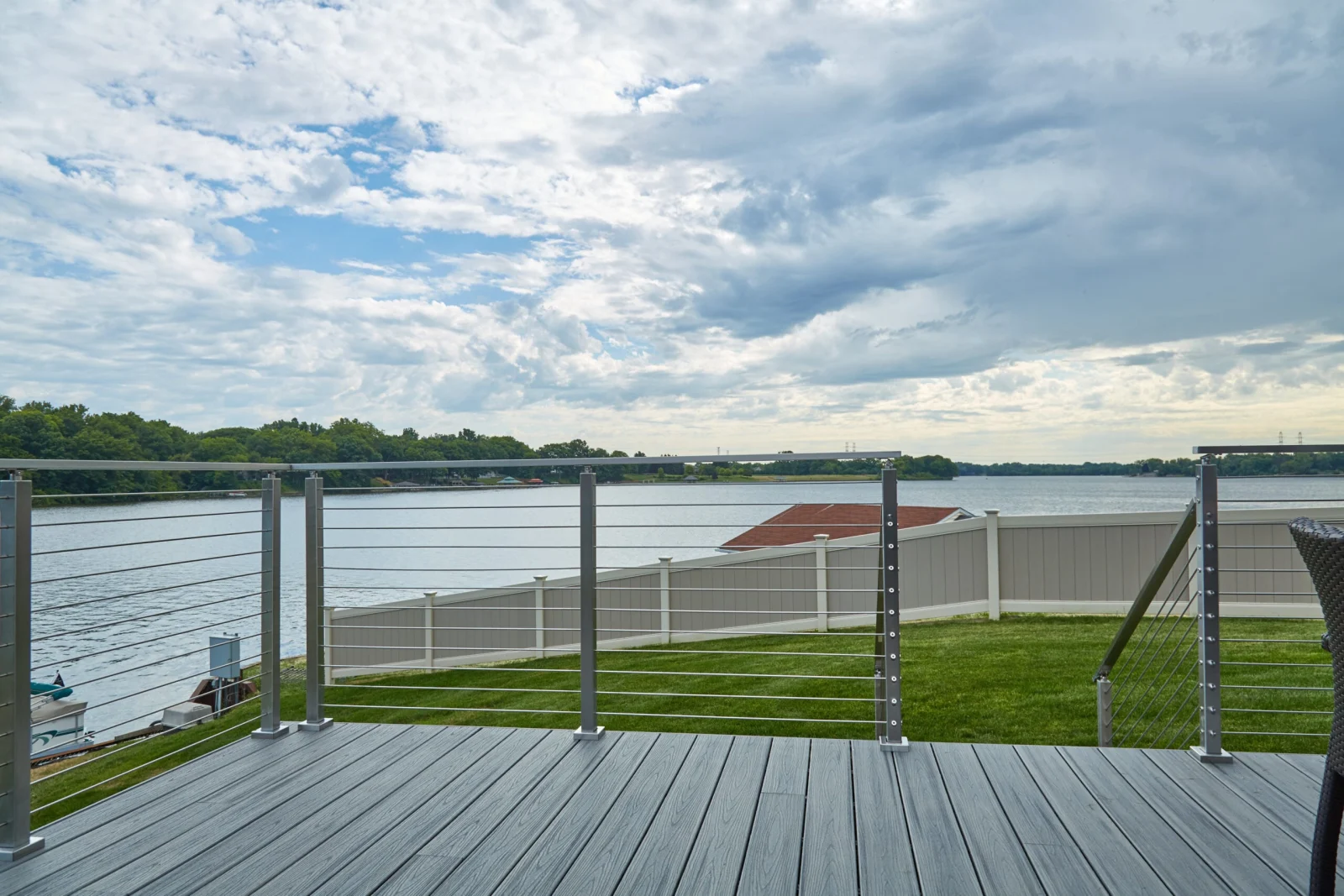 Wide-open view from a gray deck across rod railing to cloudy water