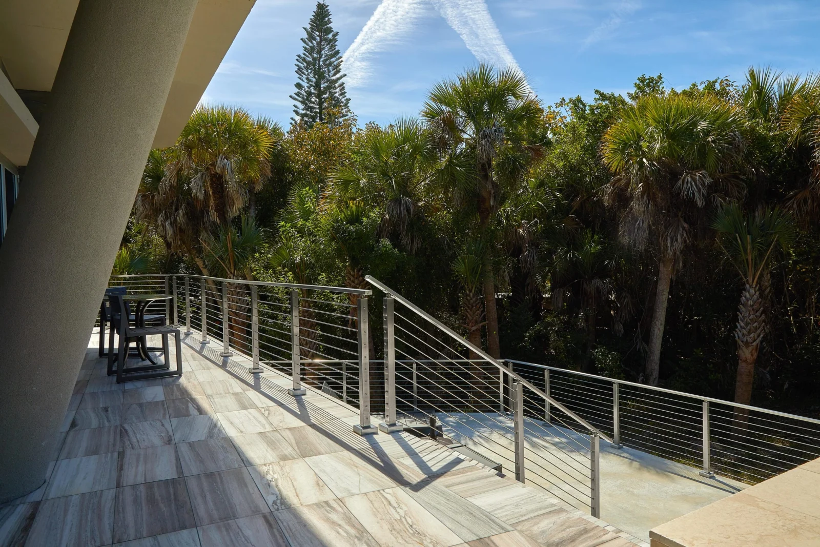 Balcony dining corner framed by horizontal rod infill and treetops