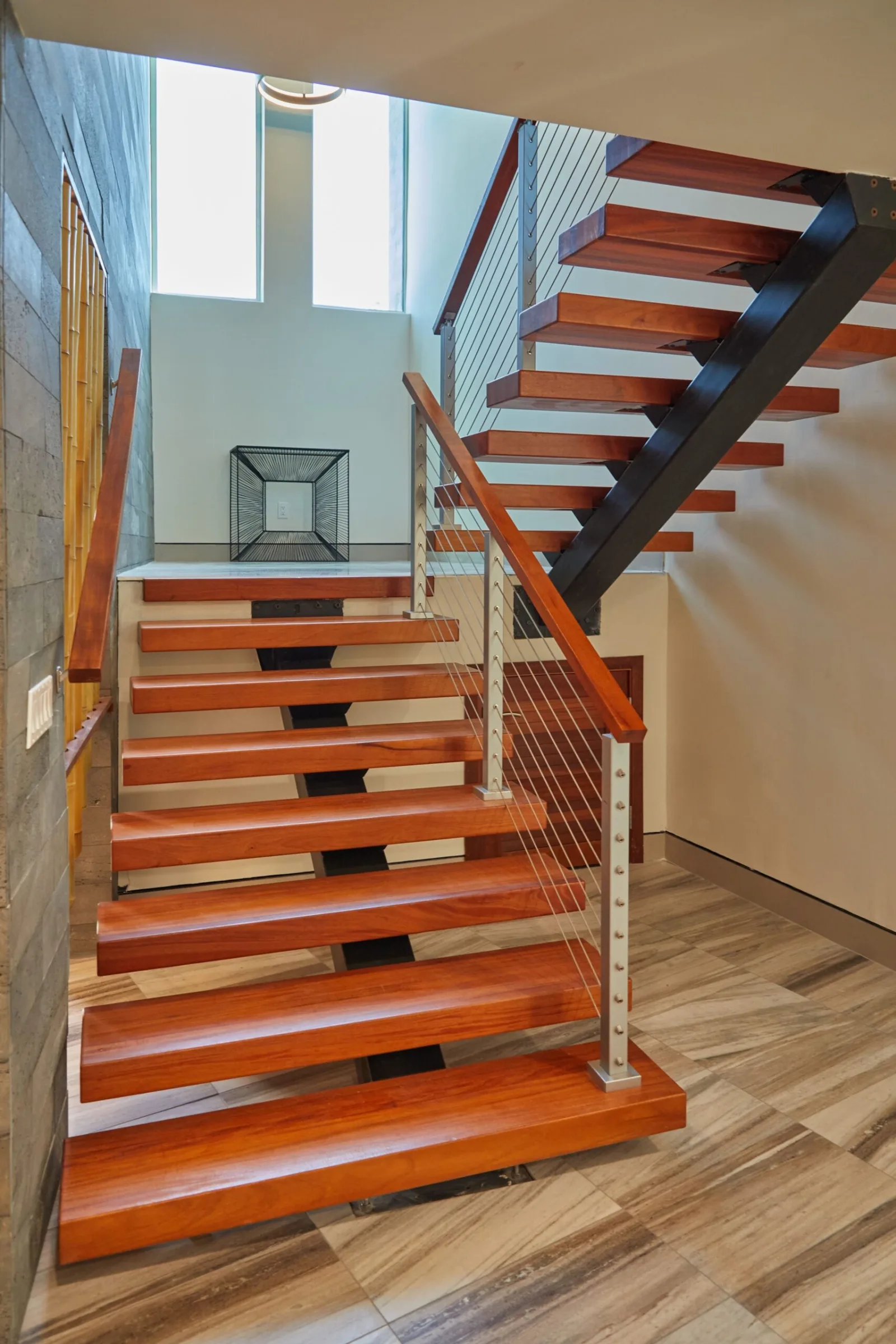 Wood tread stair and rod-filled landing rail seen from the lower floor