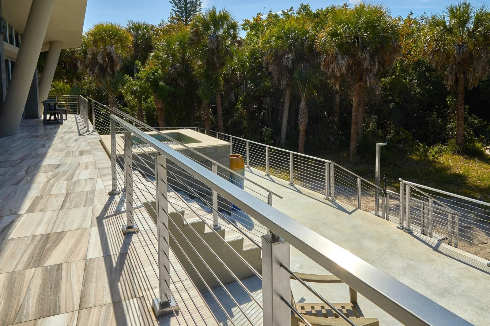 Looking down an upper deck railing toward palm canopy and the stairs below