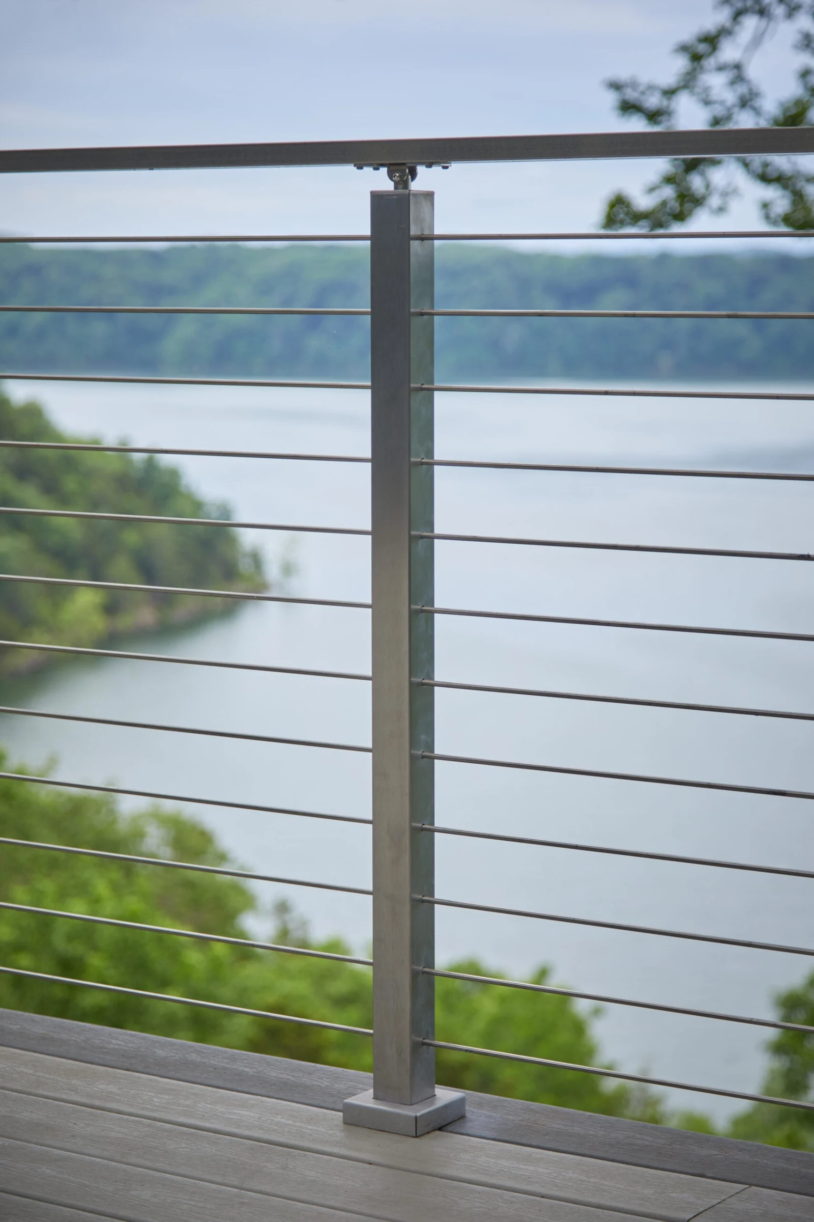 Single post and taut horizontal rods framing a broad lake and far shoreline