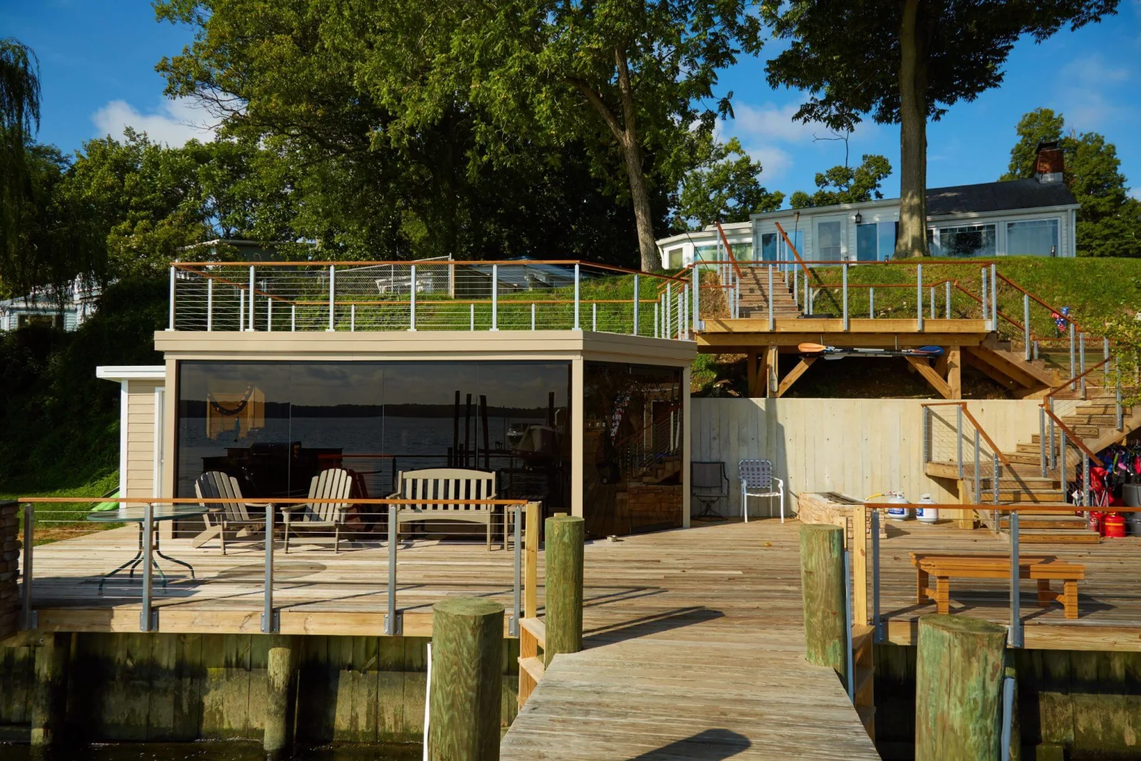 Boathouse with rooftop railing and stairs climbing the bank above a wooden dock