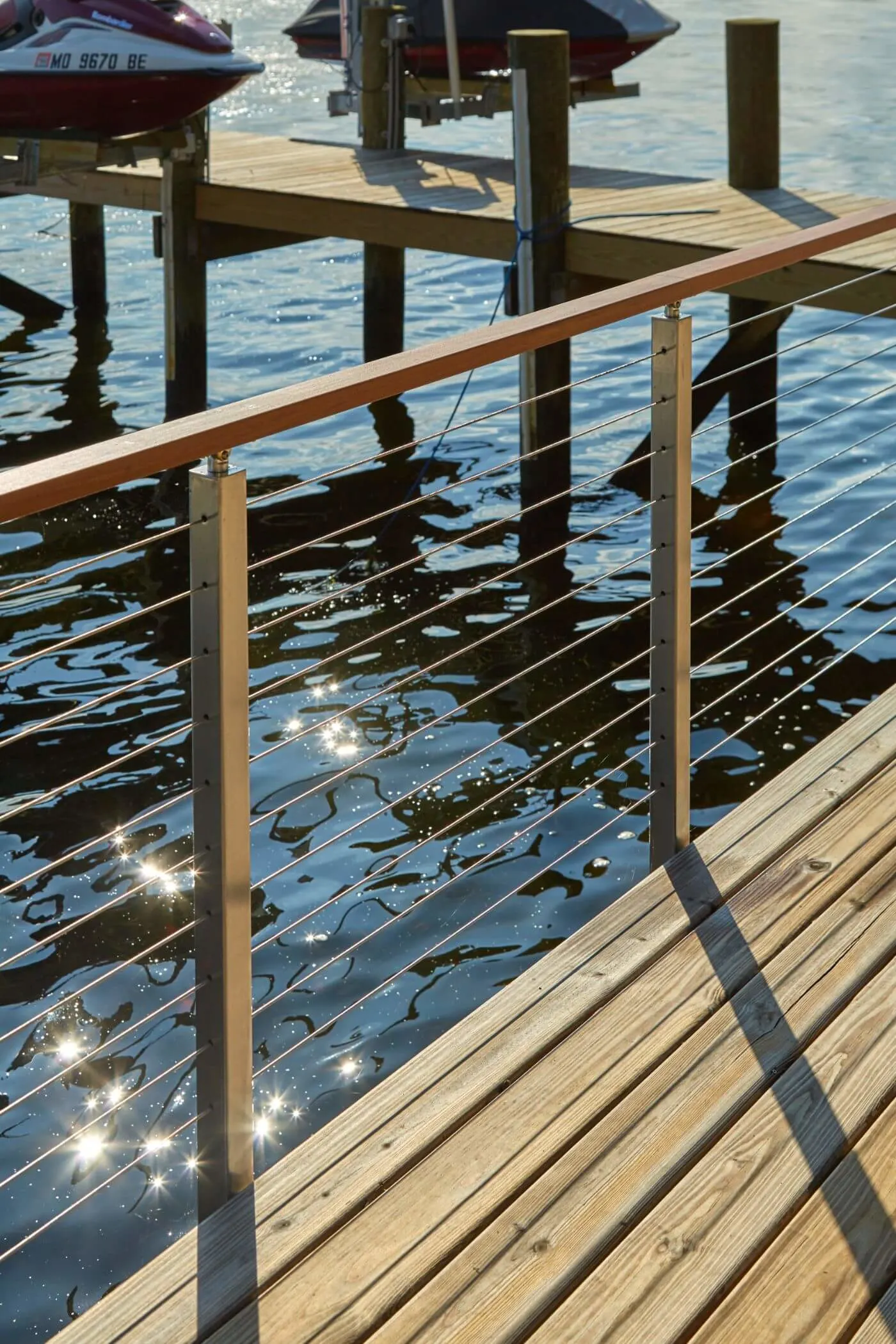 Dock railing with wood top rail and rods casting shadows on sunlit planks