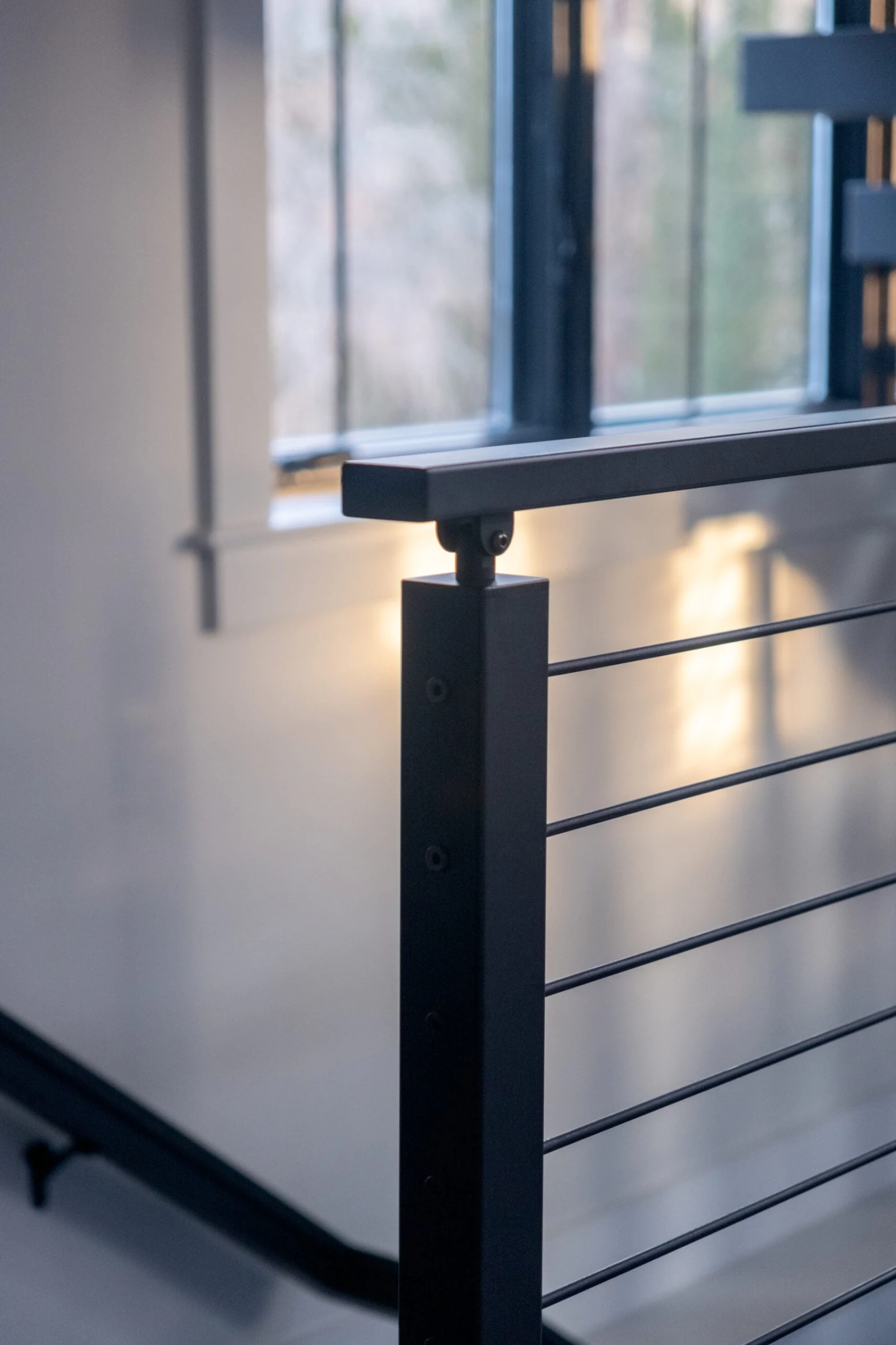 Newel post cap and rod infill lit by warm light near a window