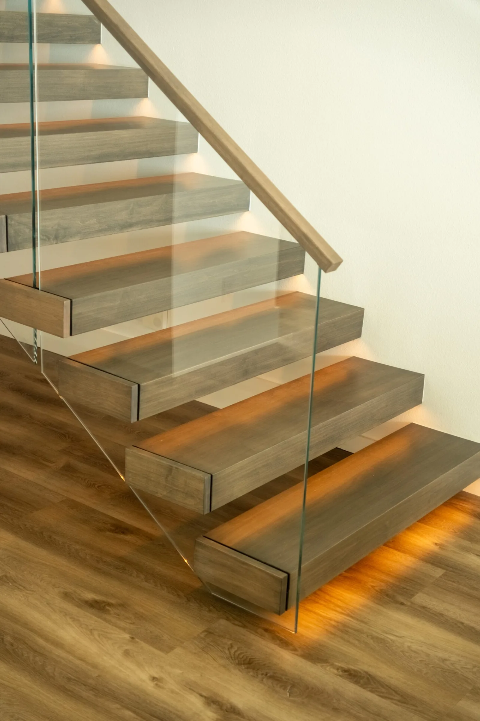 Bottom treads lit from beneath by warm LED strips beside glass panels