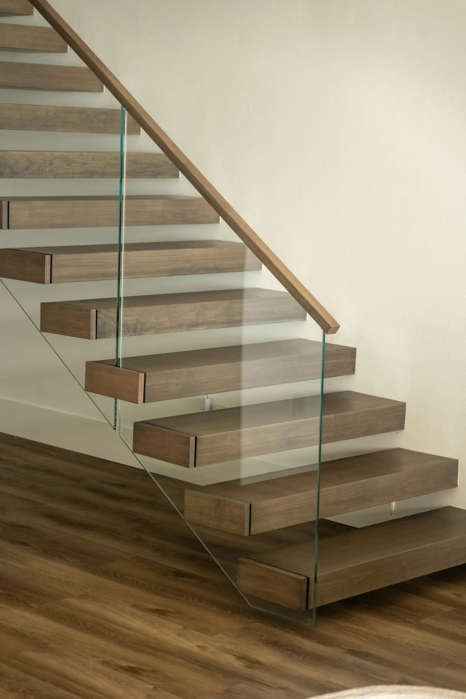 Cantilevered treads and a slim glass panel with a rounded wood handrail