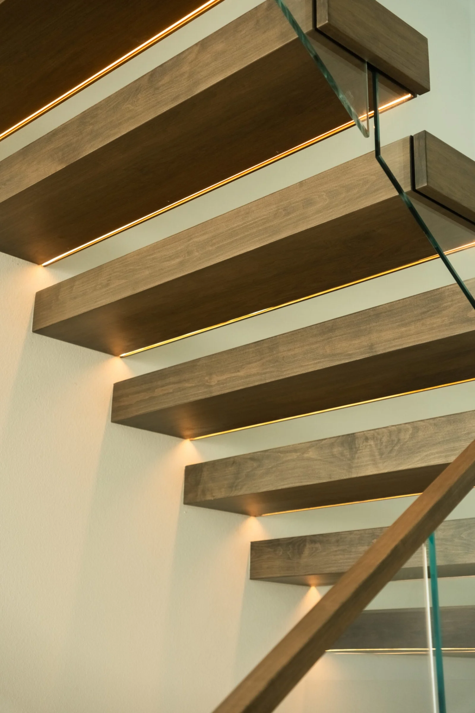 Underside of cantilevered treads with warm light washing the white wall