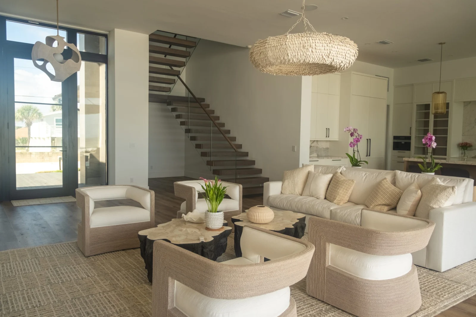 Open living room with woven pendant and a floating stair rising behind the seating