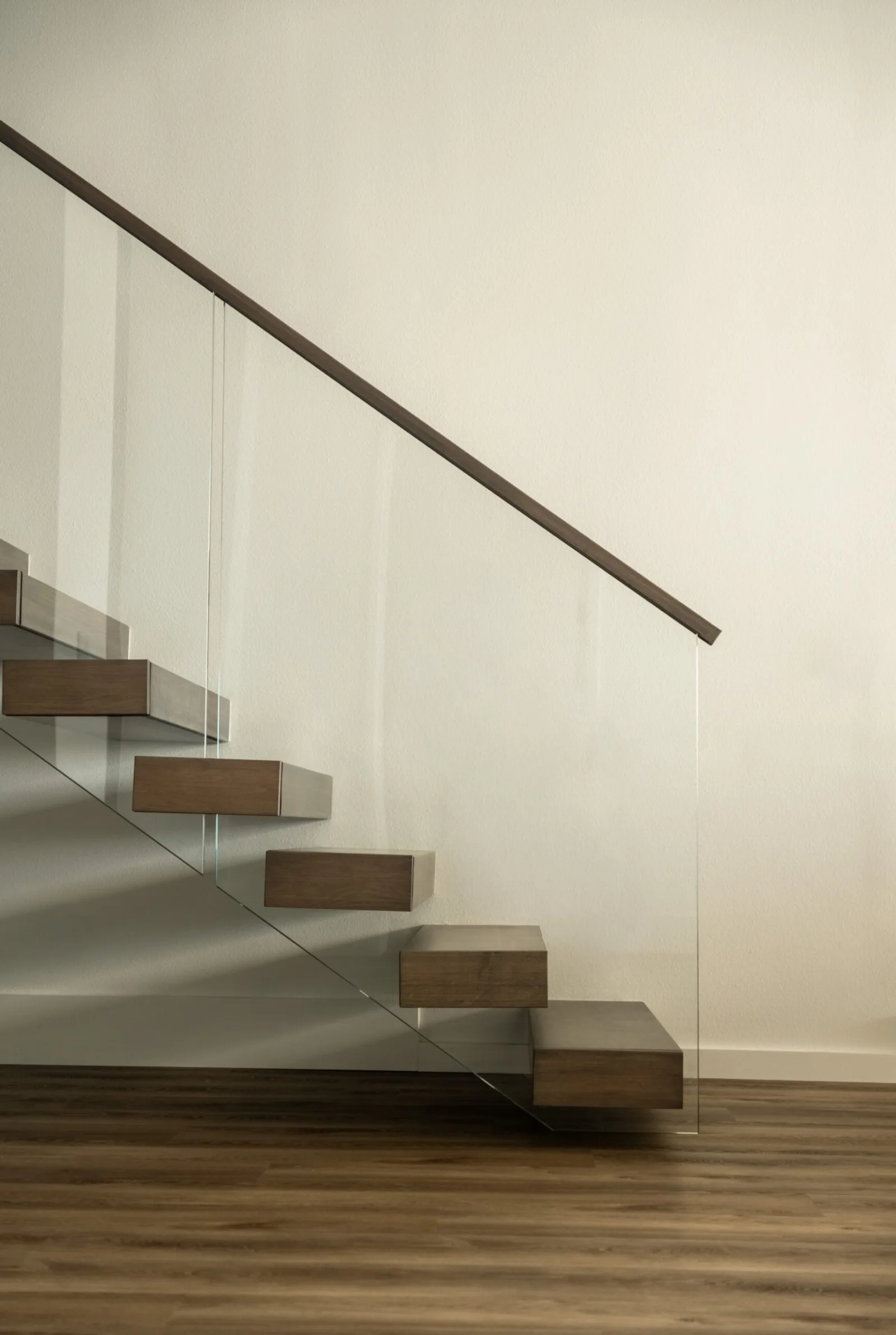 Floating stair in profile against a white wall with full-height glass railing