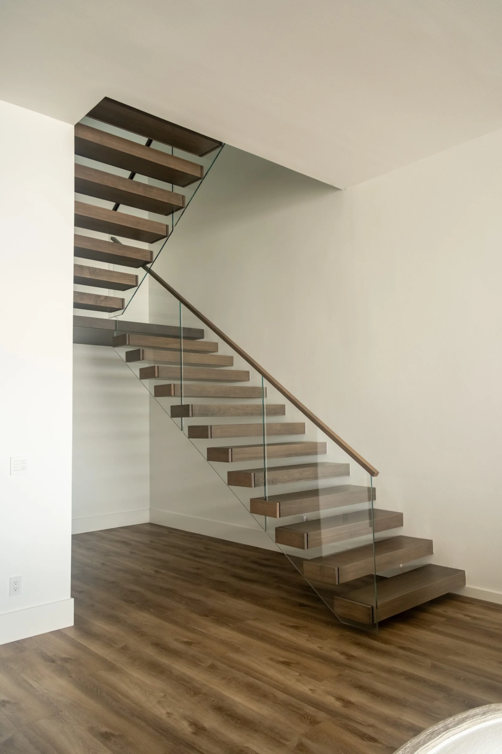 Full flight with mid-landing, glass railing and wood handrail over plank floor