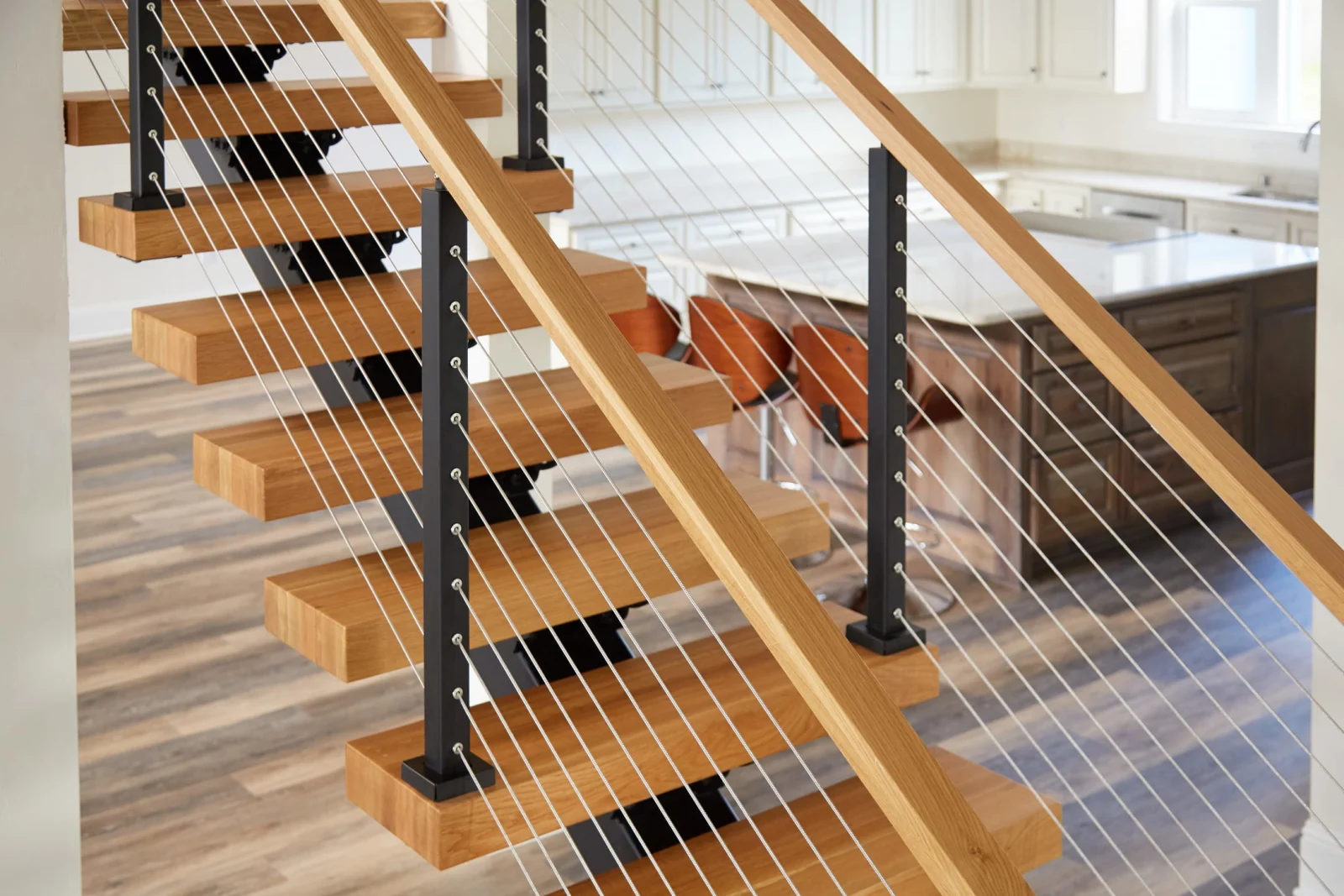 Cable railing with black posts and wood top rail in front of the kitchen