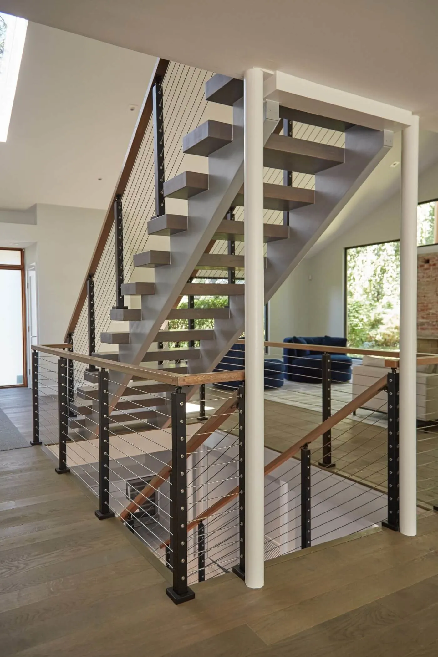 Stair and balcony cable railing runs wrapping an open entry with white column