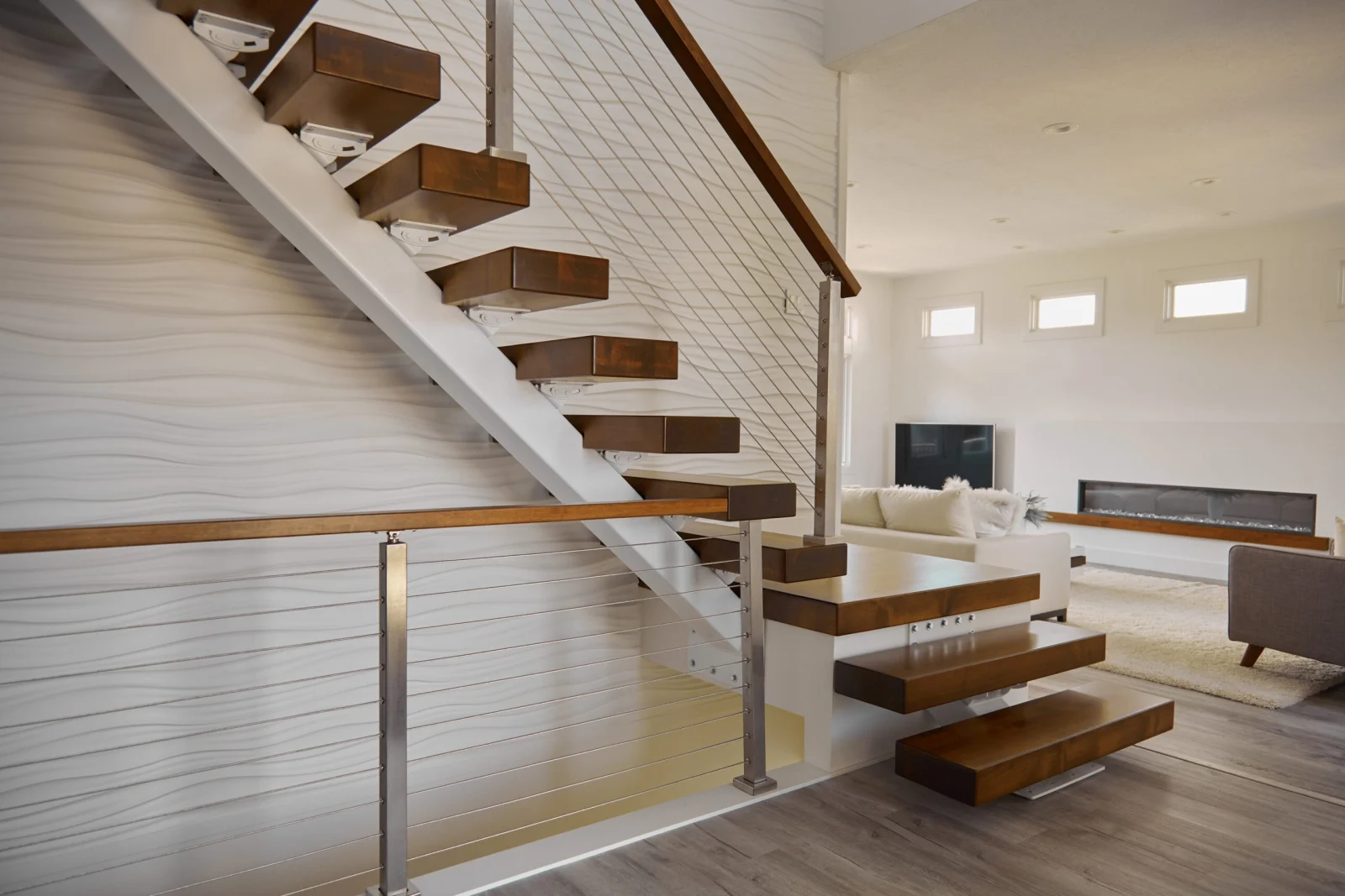 Floating stair turning ninety degrees on a white stringer against a textured wall