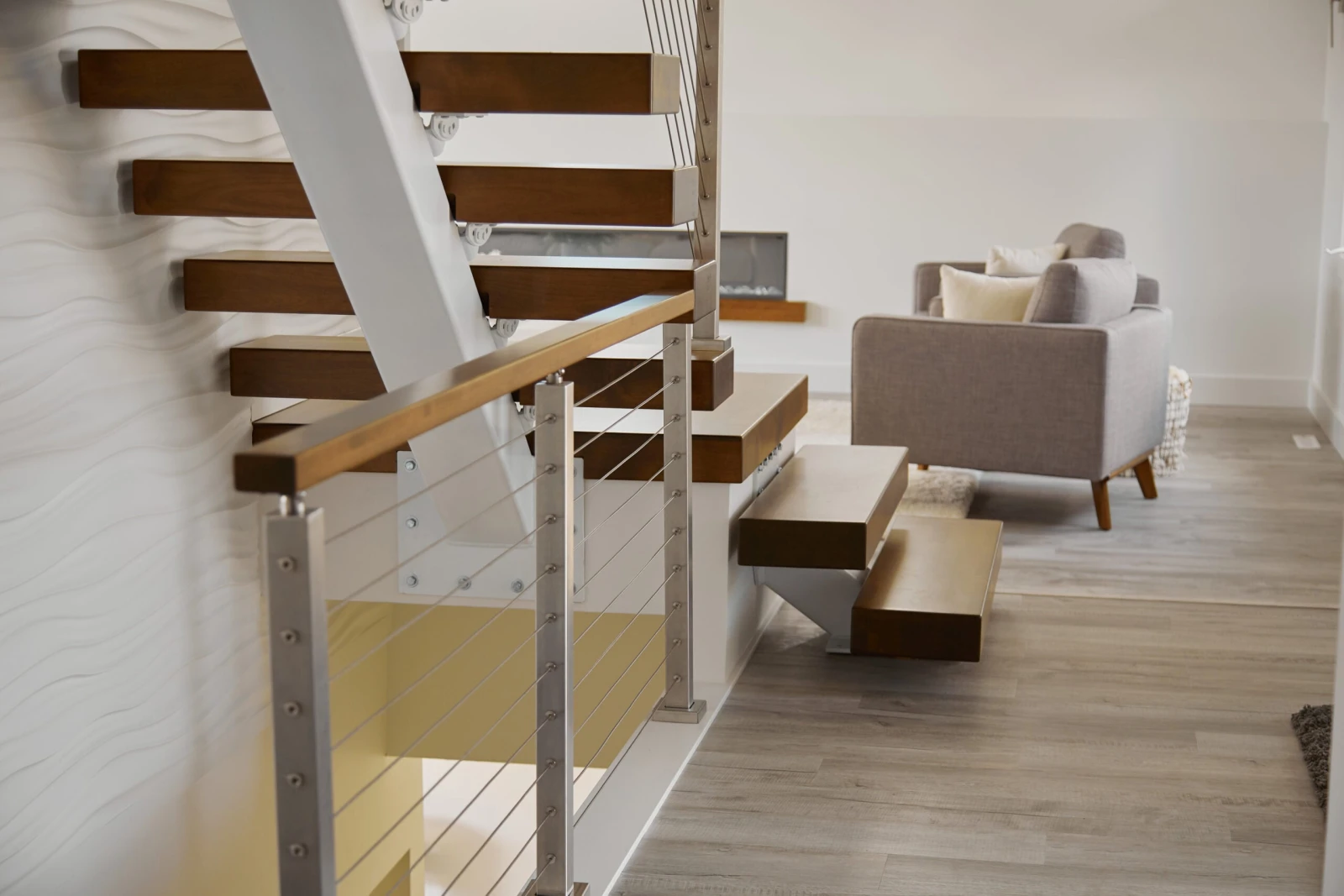Wood treads cantilevered from a white center stringer above a cable-railed landing
