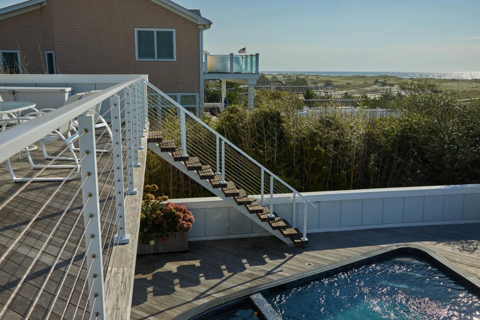 Deck railing and stair with a spa and dune grass in the distance