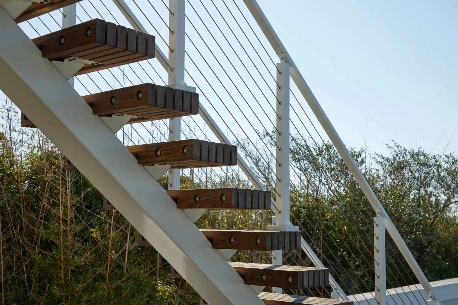 White stringer and open treads seen from below against a clear sky