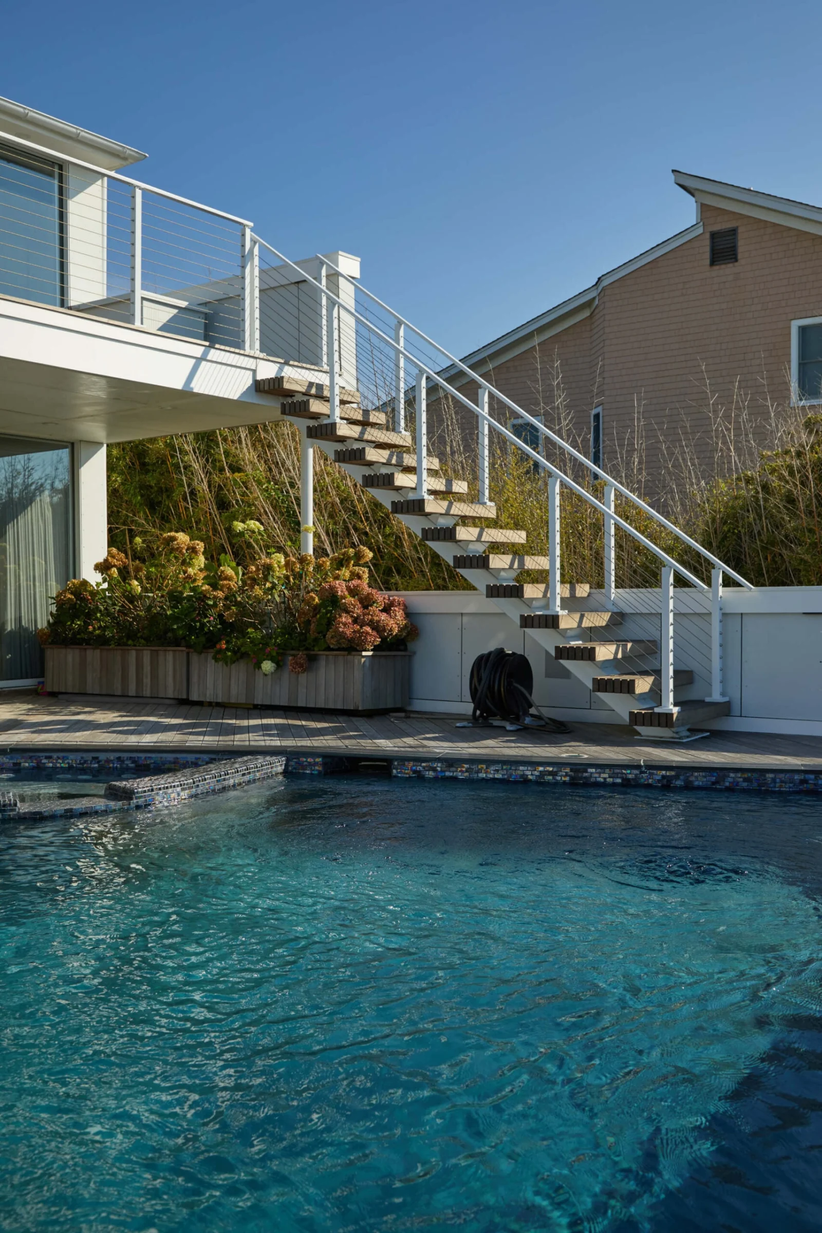 Stair climbing from the pool deck to an upper balcony with cable railing