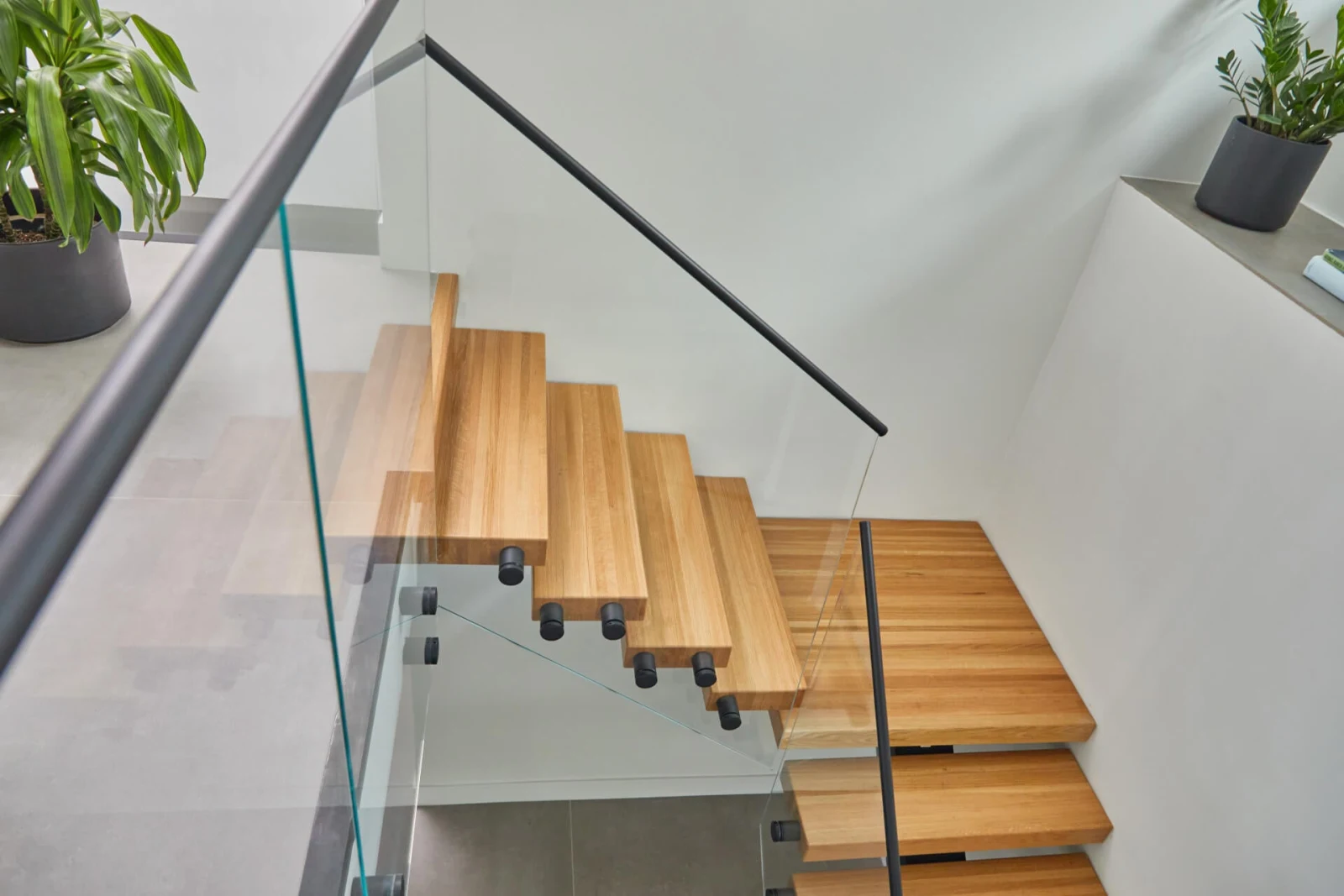Overhead view of wood treads with glass panels held by black standoff pins