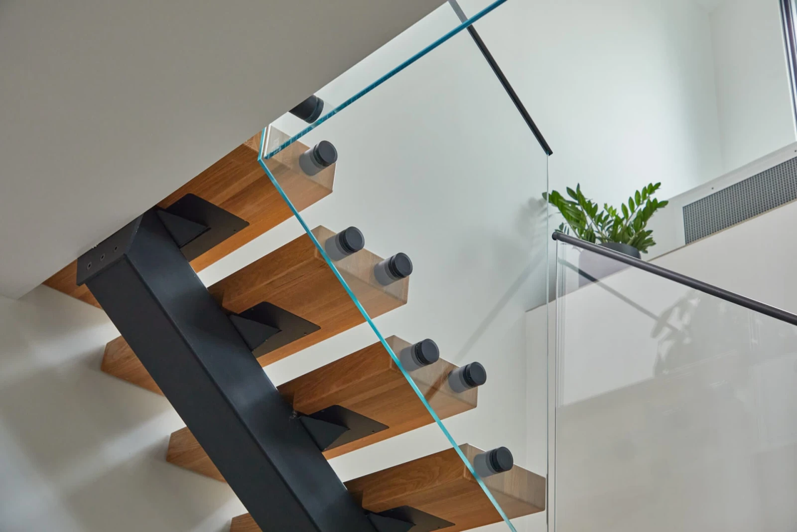 Black stringer and pinned glass panels seen from beneath the open treads