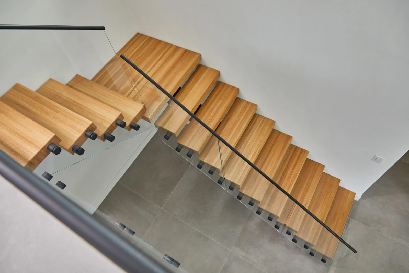 Wide treads and glass panels viewed from the upper floor near a planter