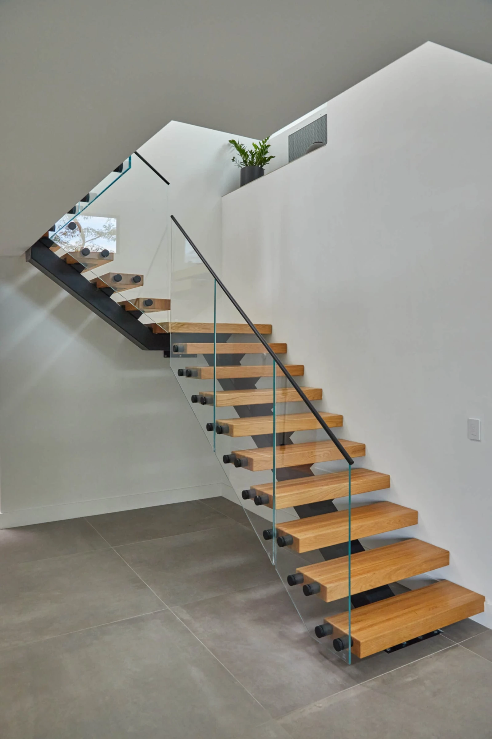 Full flight and upper landing wrapped in frameless glass above concrete floors
