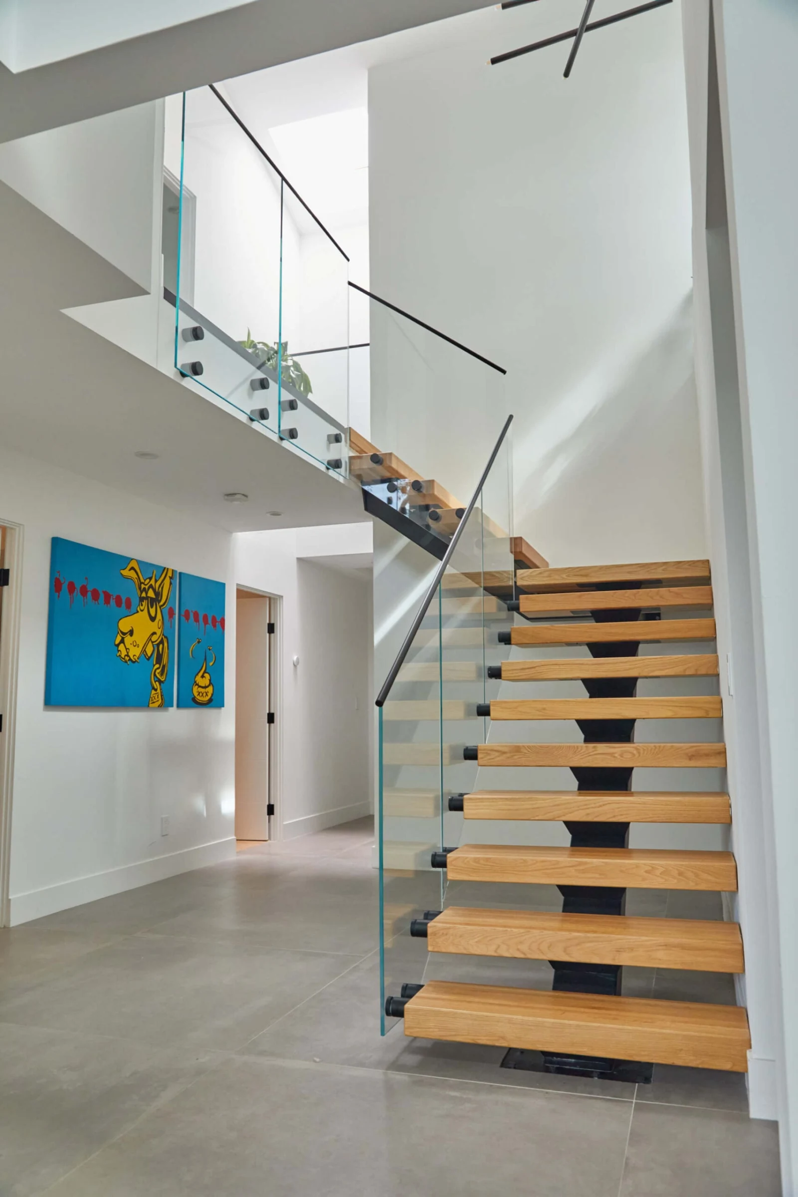 Looking down at the landing where the gray handrail turns above the treads