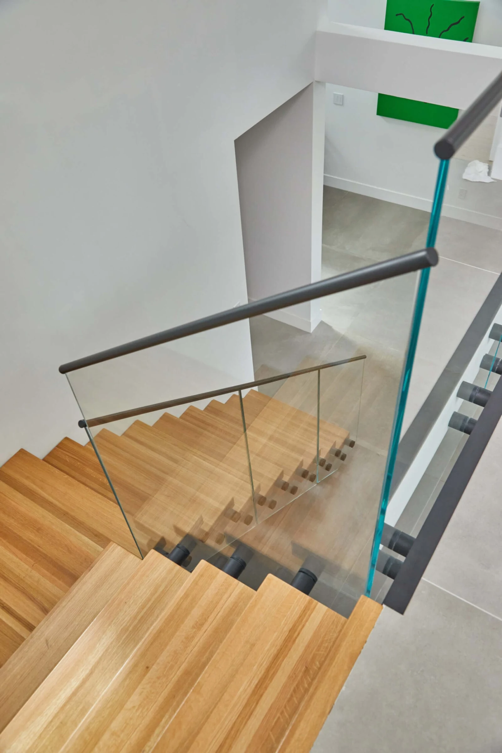 Overhead view down the flight with a slim black handrail crossing the treads