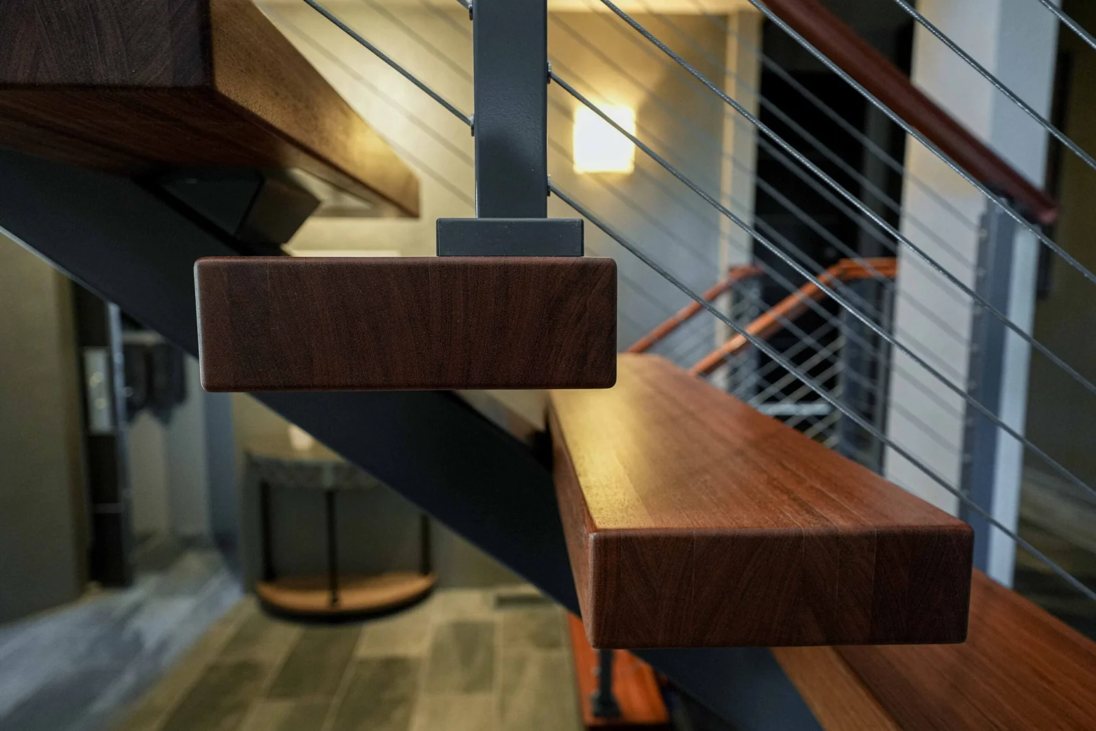 Close view of a reddish wood top rail ending above a black post
