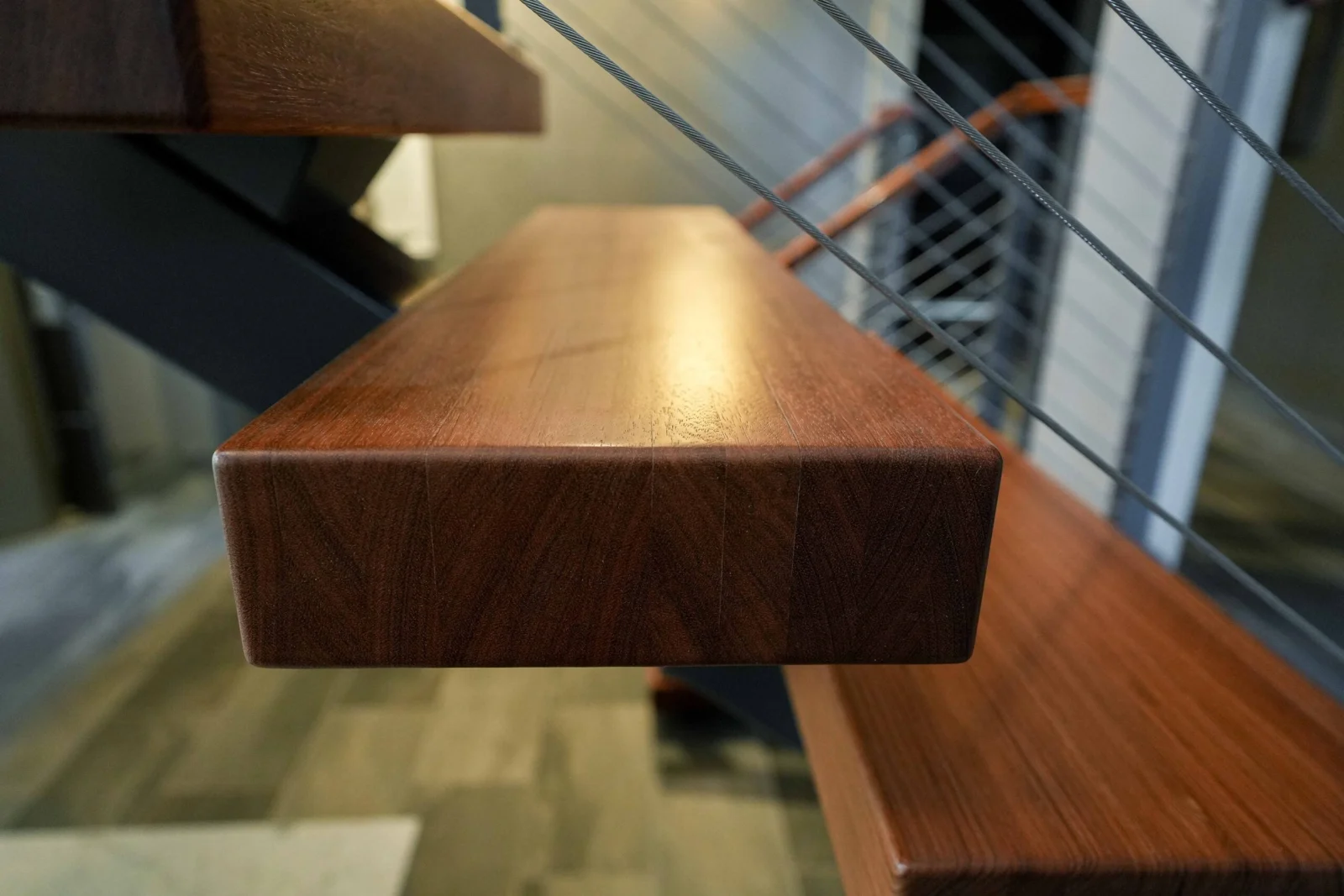 Wood top rail catching light with taut cables running behind it
