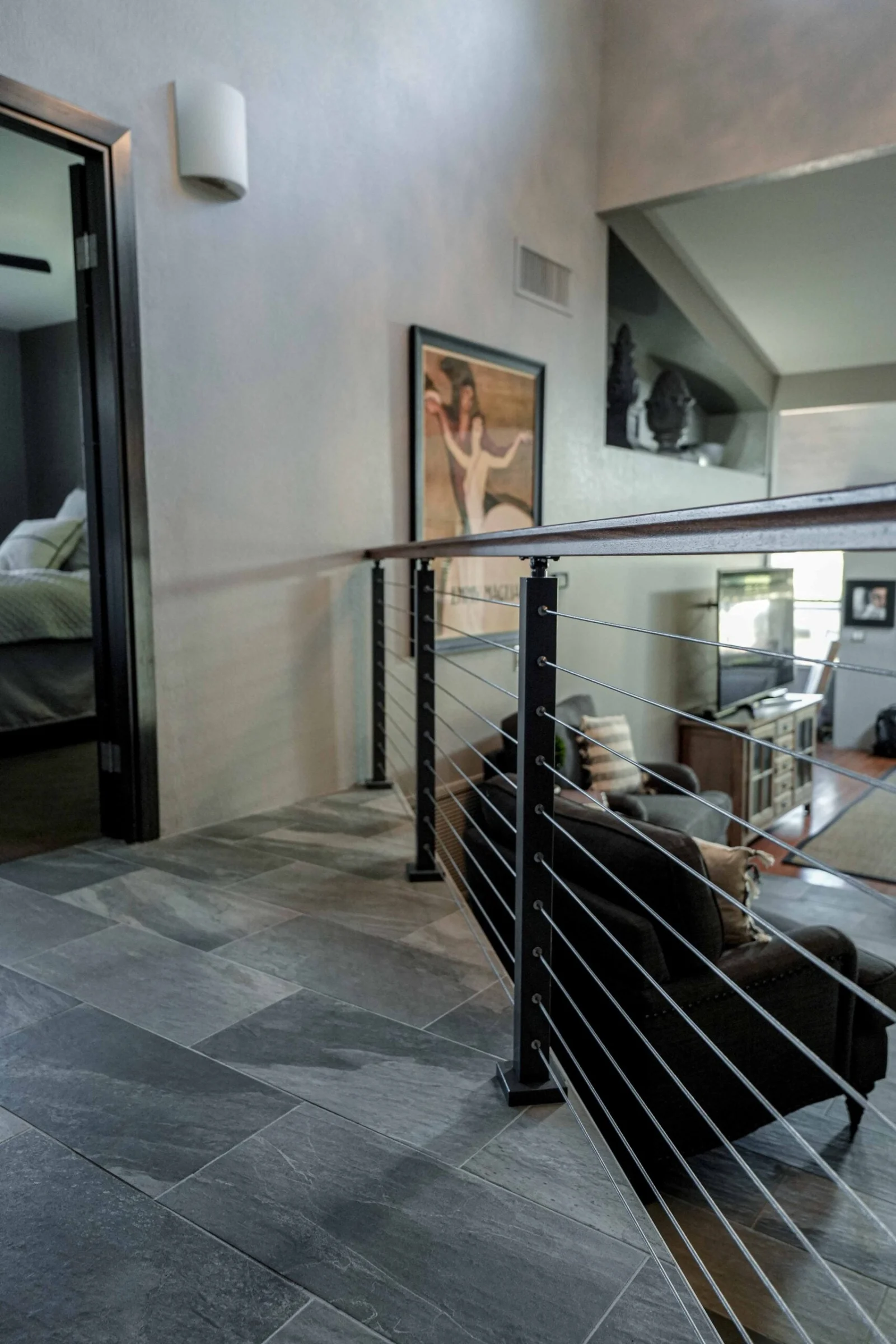 Second-floor balcony run of cable railing beside a stone-tiled hallway