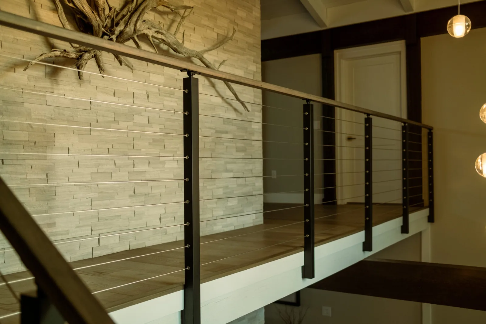Cable railing running along a balcony beside a stacked stone accent wall